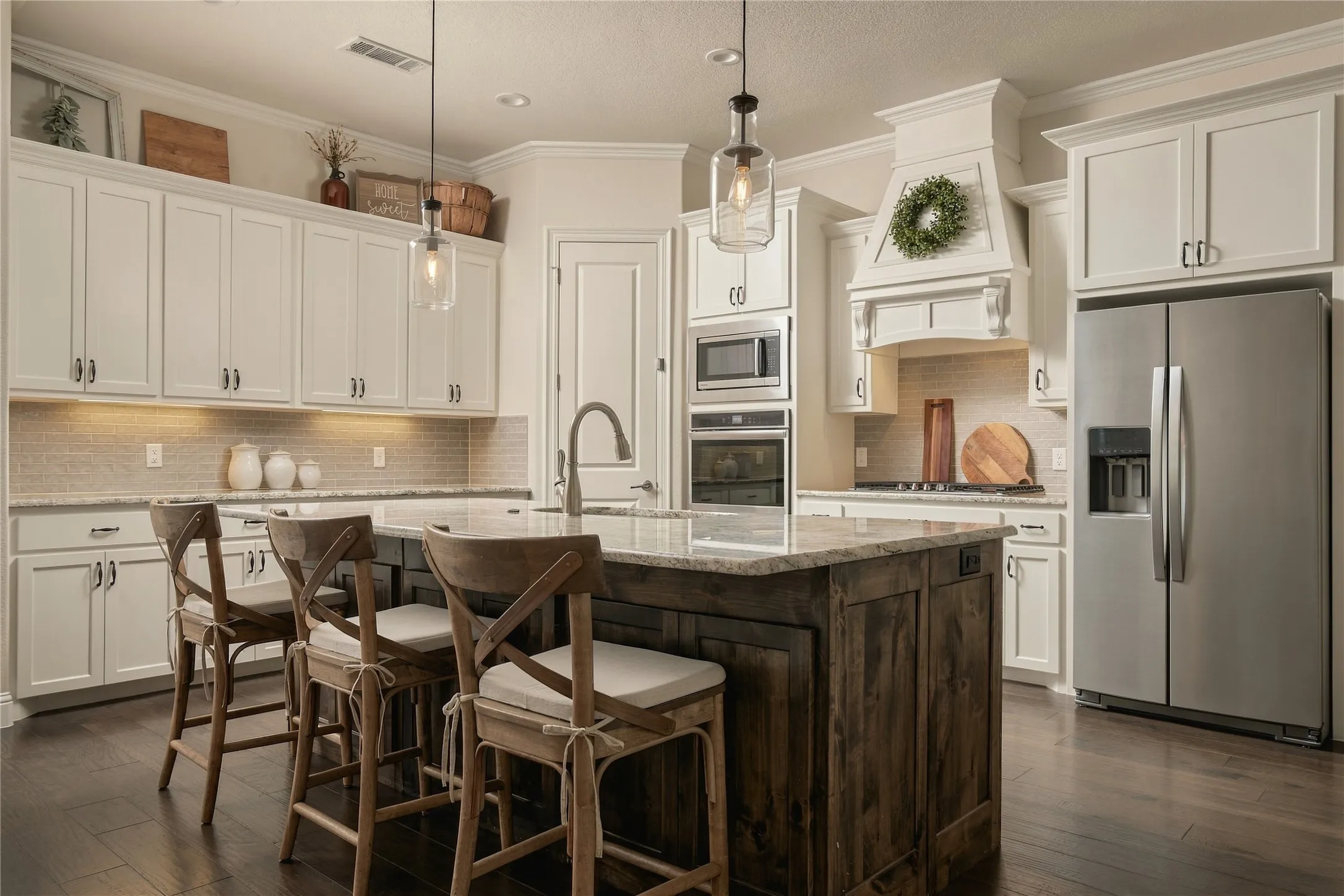 A bright, generously sized kitchen pairs extensive cabinetry, stone countertops, stainless appliances and an oversized island built for everyday gathering.