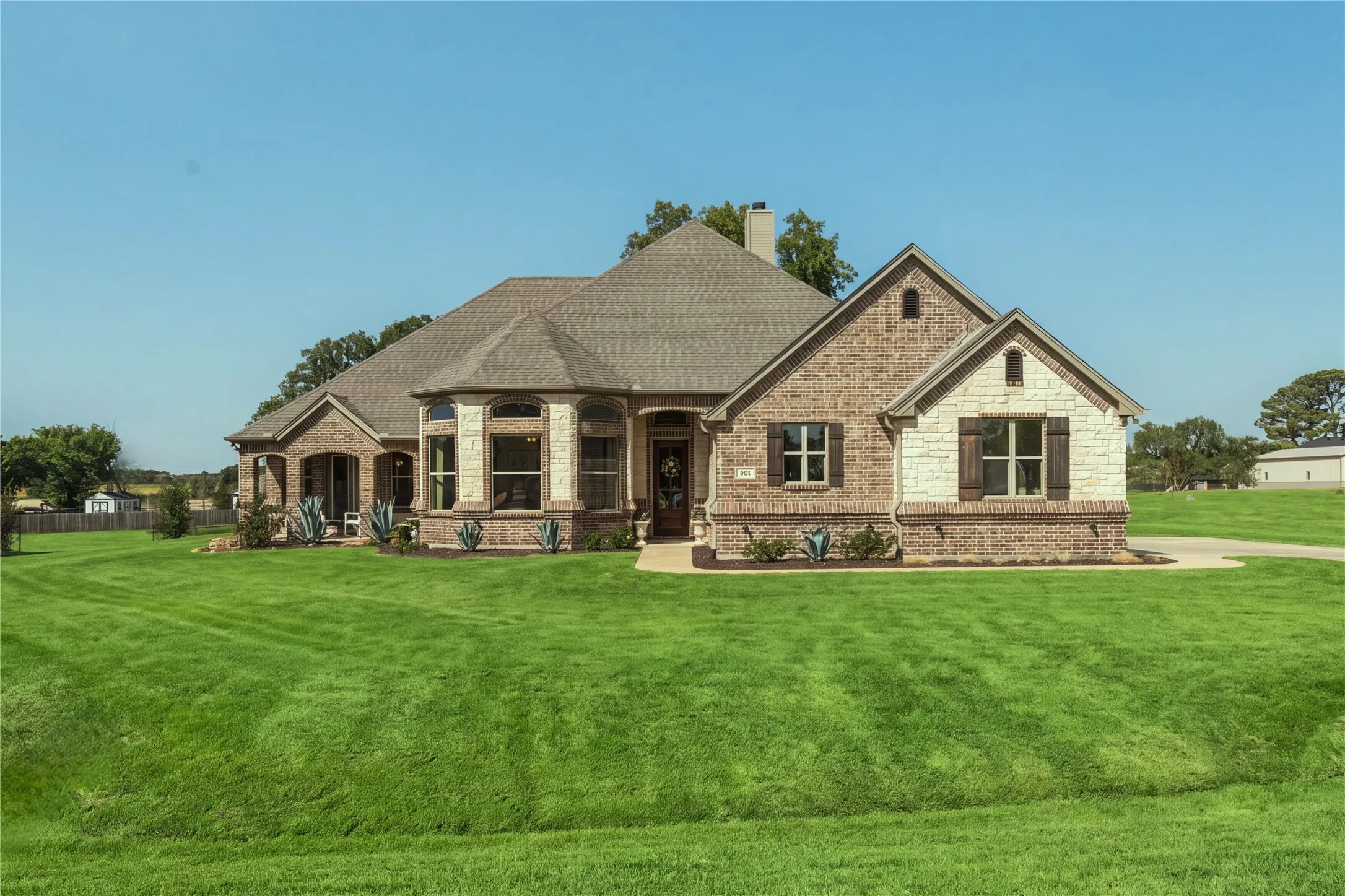 Brick and stone architecture, established lawn and mature trees give this 2020-built home a sense of permanence rarely found in newer construction.