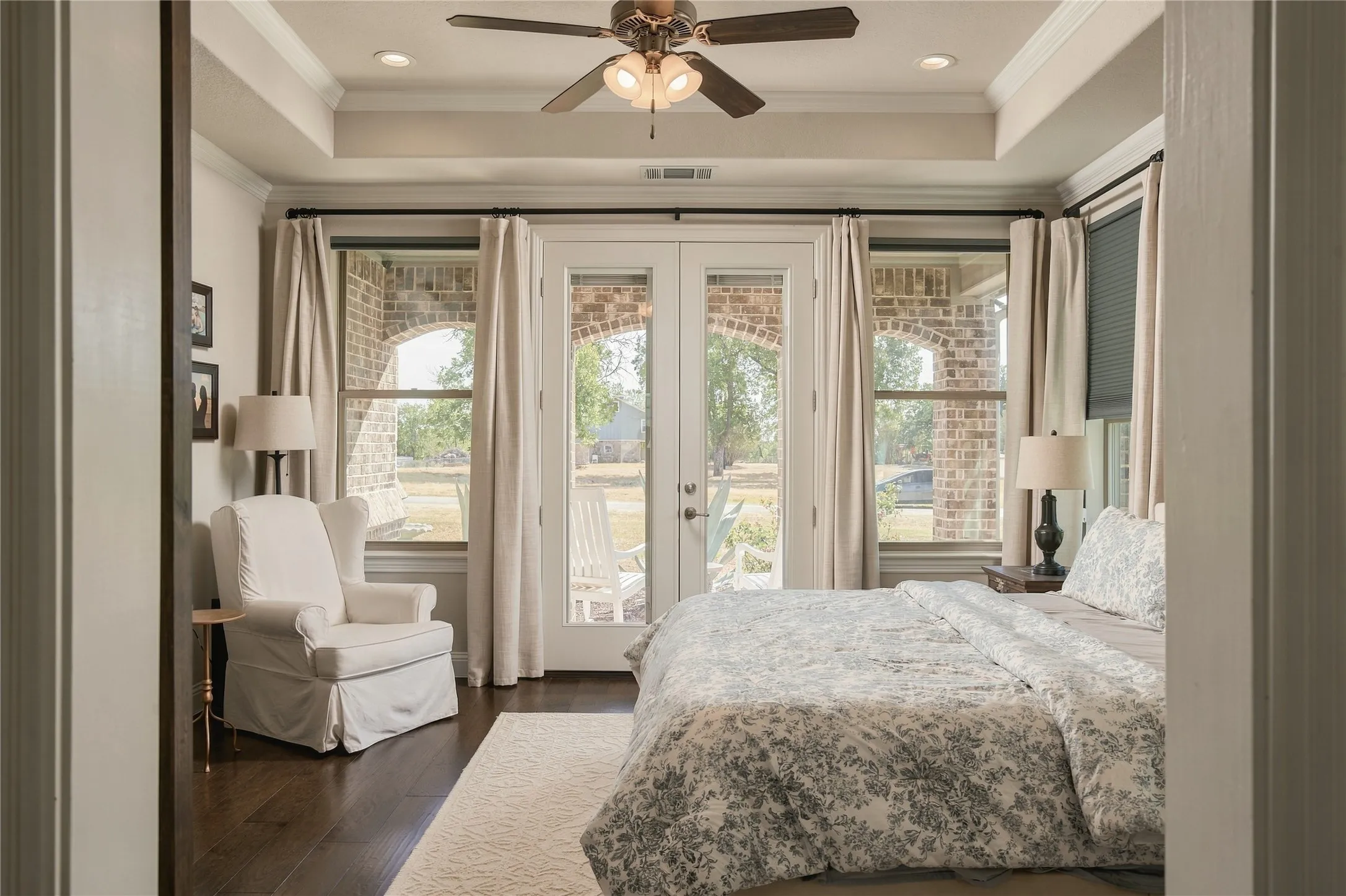 Tray ceilings, crown molding and hardwood floors add architectural polish to a primary suite designed for both comfort and scale.