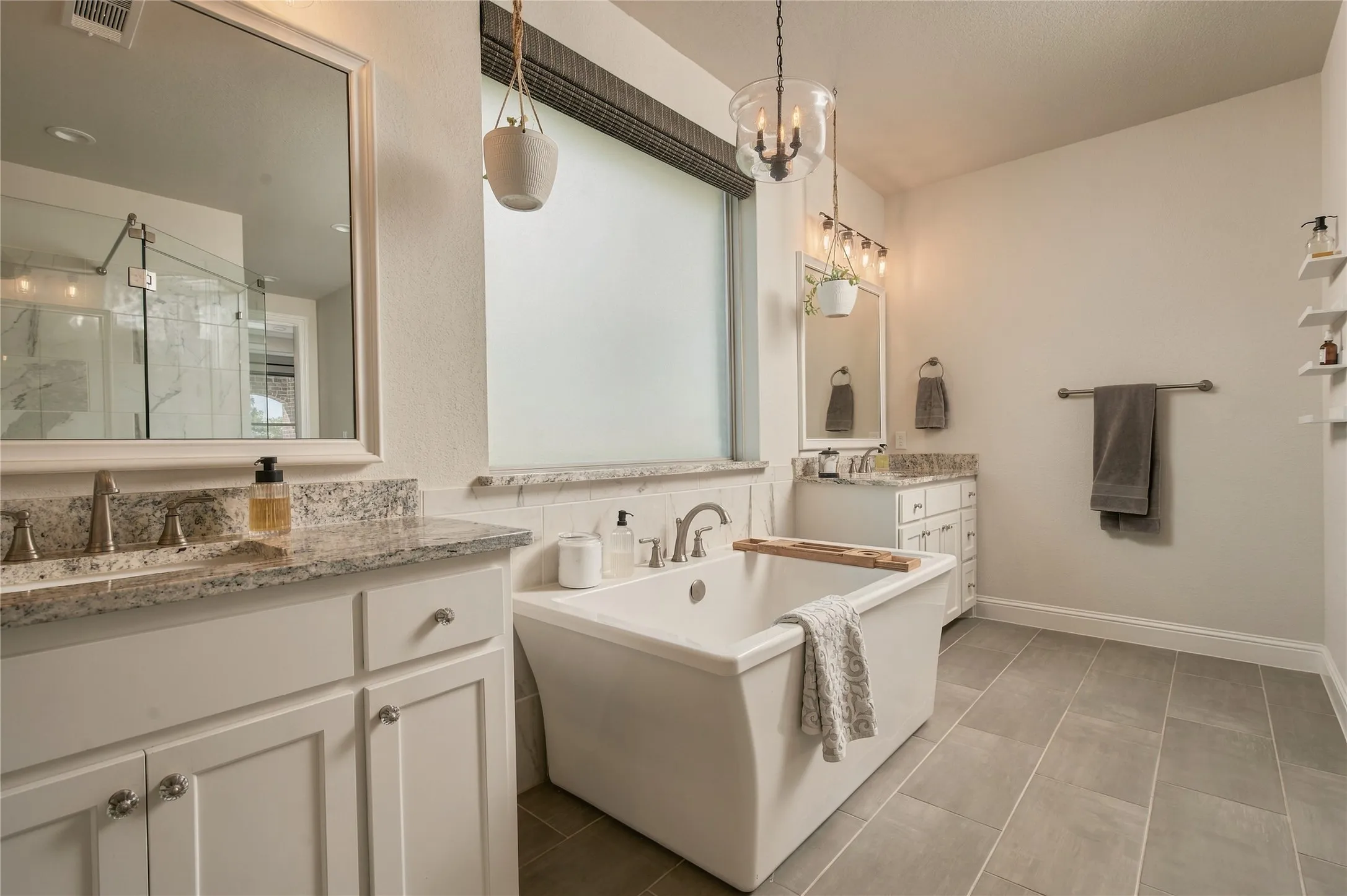 A freestanding soaking tub takes center stage in the spa-inspired primary bath, complemented by dual vanities and generous natural light.