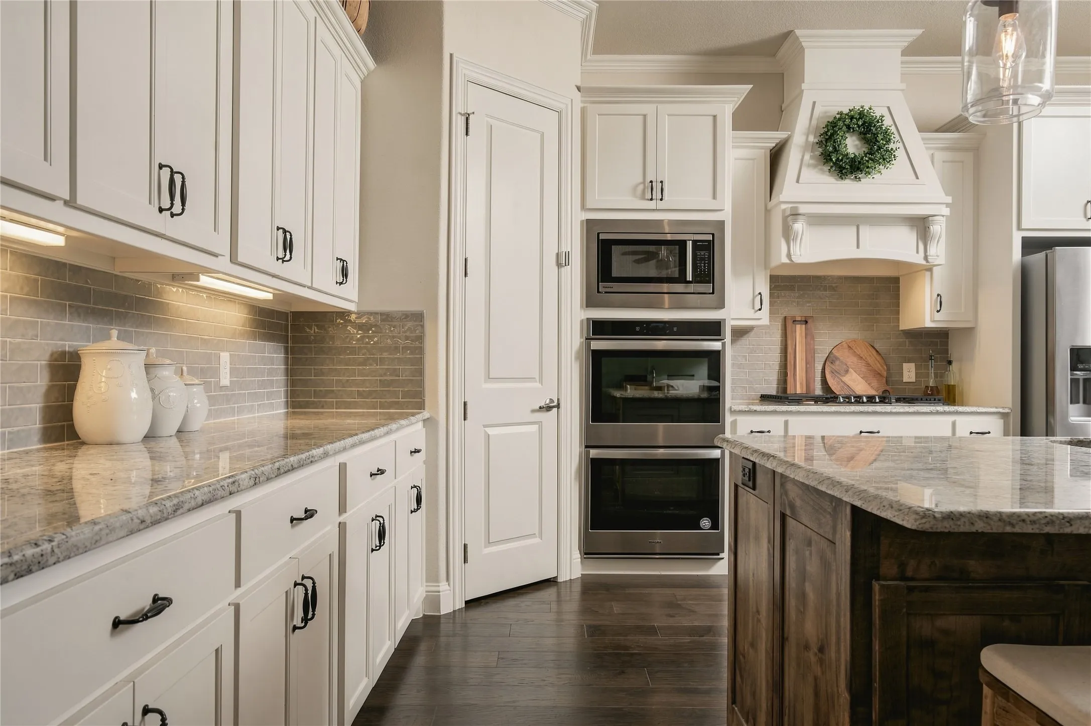 Extensive white cabinetry, stone countertops and stainless appliances, including a double oven, create a timeless kitchen designed for everyday function and effortless entertaining.