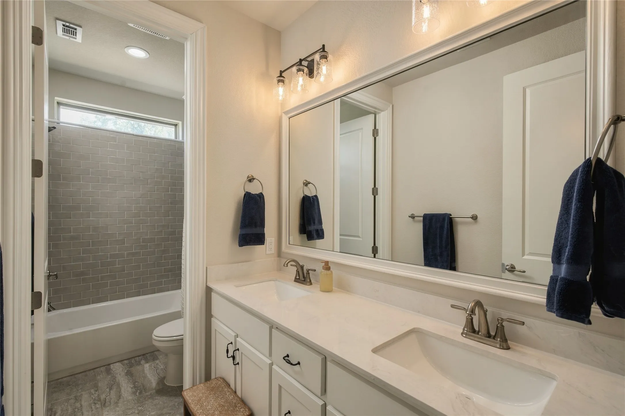 A dual-sink vanity provides practical separation and storage, making the secondary bath well suited for shared everyday use.