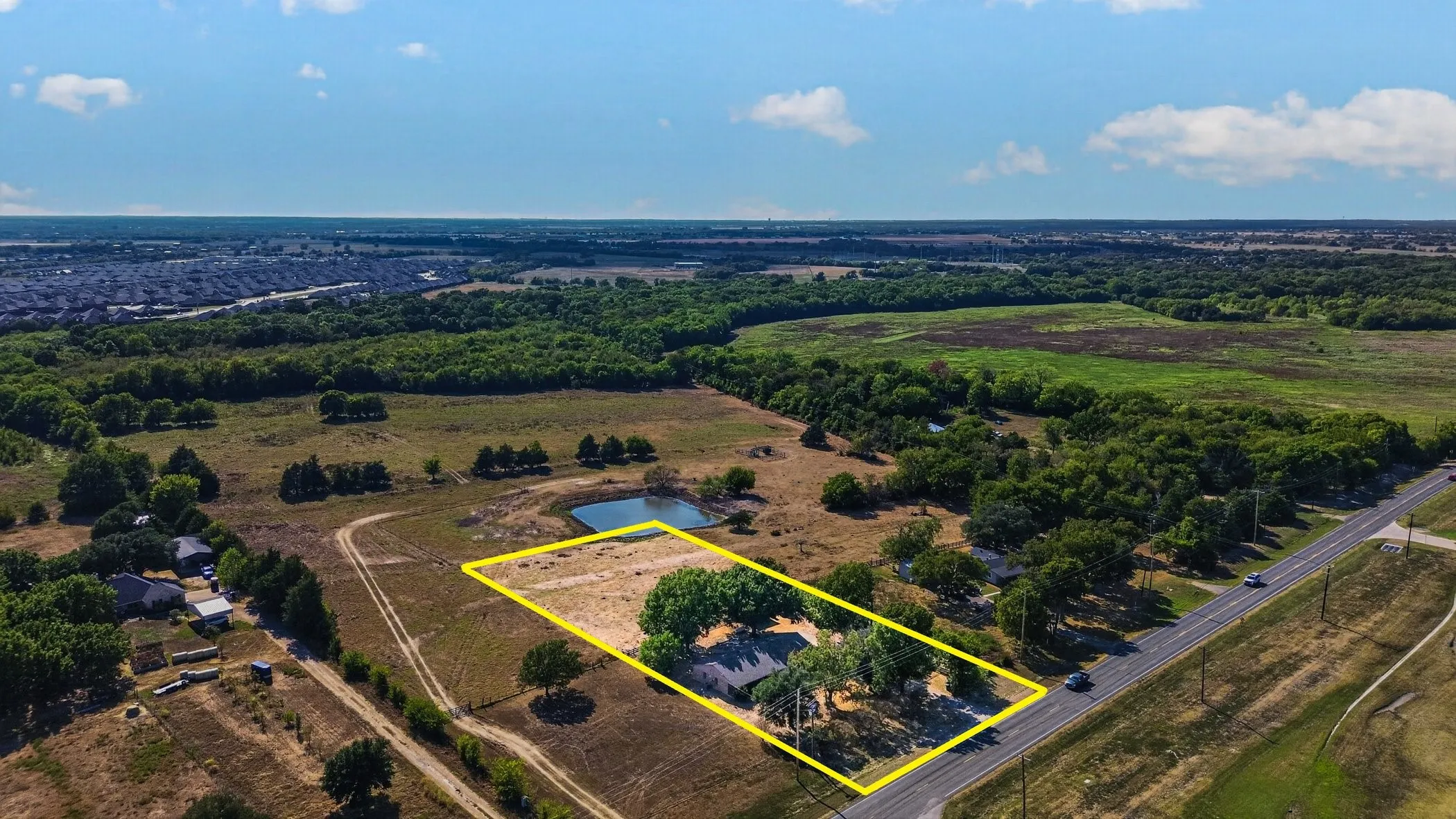 Expansive property featuring a pond, mature trees, and direct road frontage