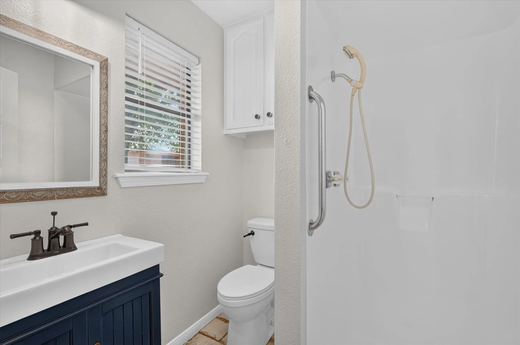 White shower enclosure with grab bar and handheld shower fixture
