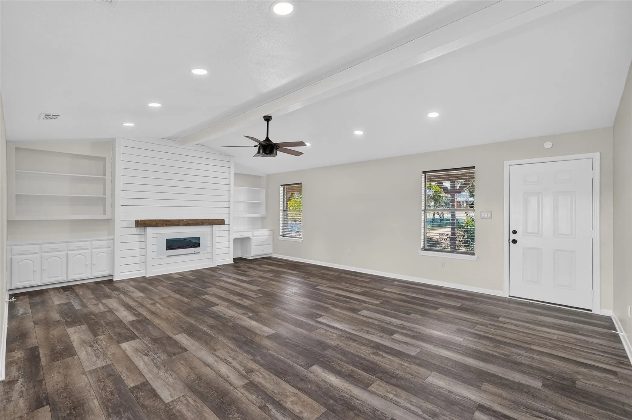 Spacious living area featuring wood-finish flooring, vaulted ceiling with beam detail, recessed lighting, and a ceiling fan