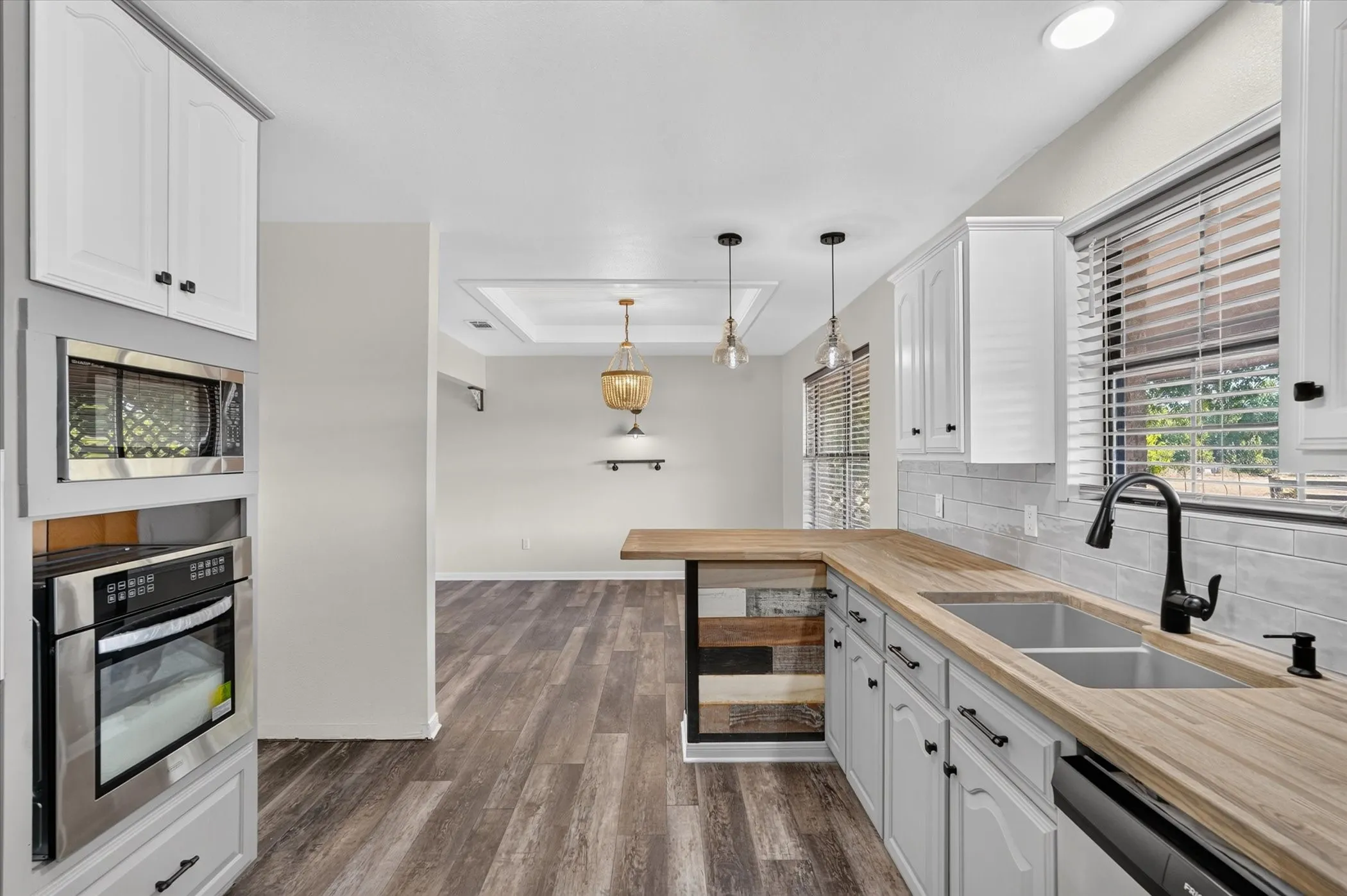 Kitchen with wood-finish countertops, subway tile backsplash, stainless steel appliances, and pendant lighting