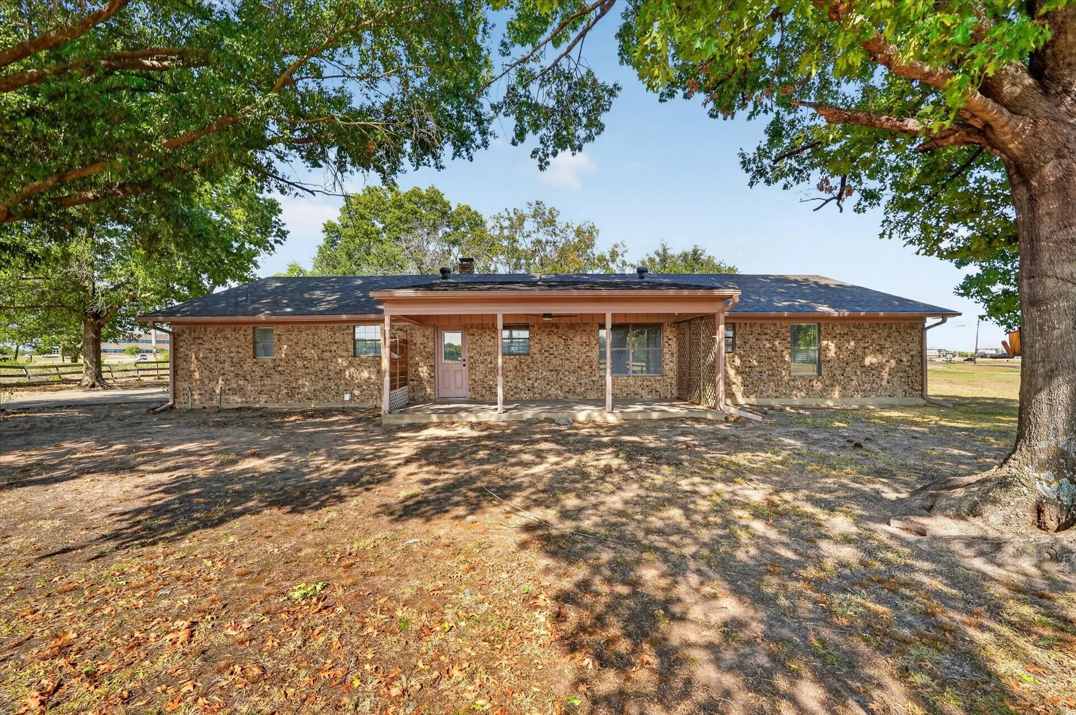 Brick exterior with a covered patio, featuring a dark shingle roof and multiple windows