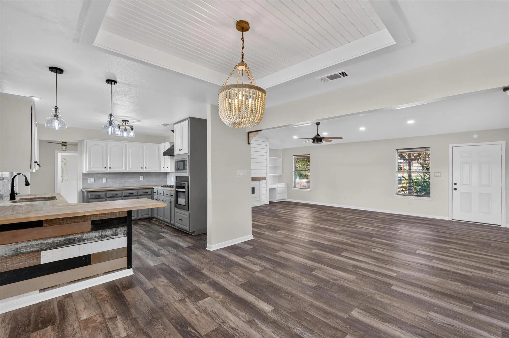 Wood-finish flooring throughout, tray ceiling with beadboard detail, recessed lighting, and a kitchen island with a wood-finish countertop