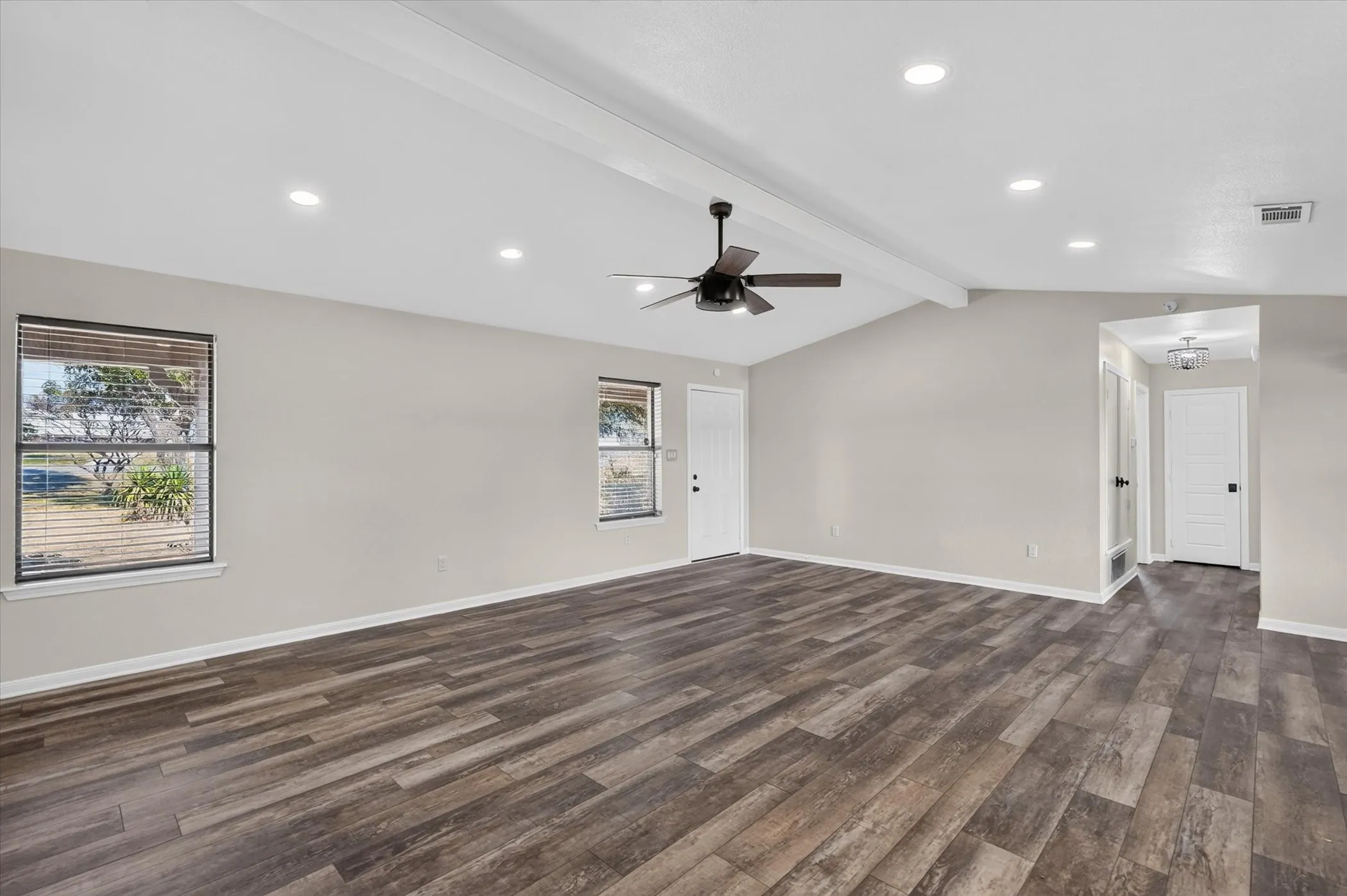 Vaulted ceiling with exposed beam, wood-finish flooring, recessed lighting, ceiling fan, and white paneled doors