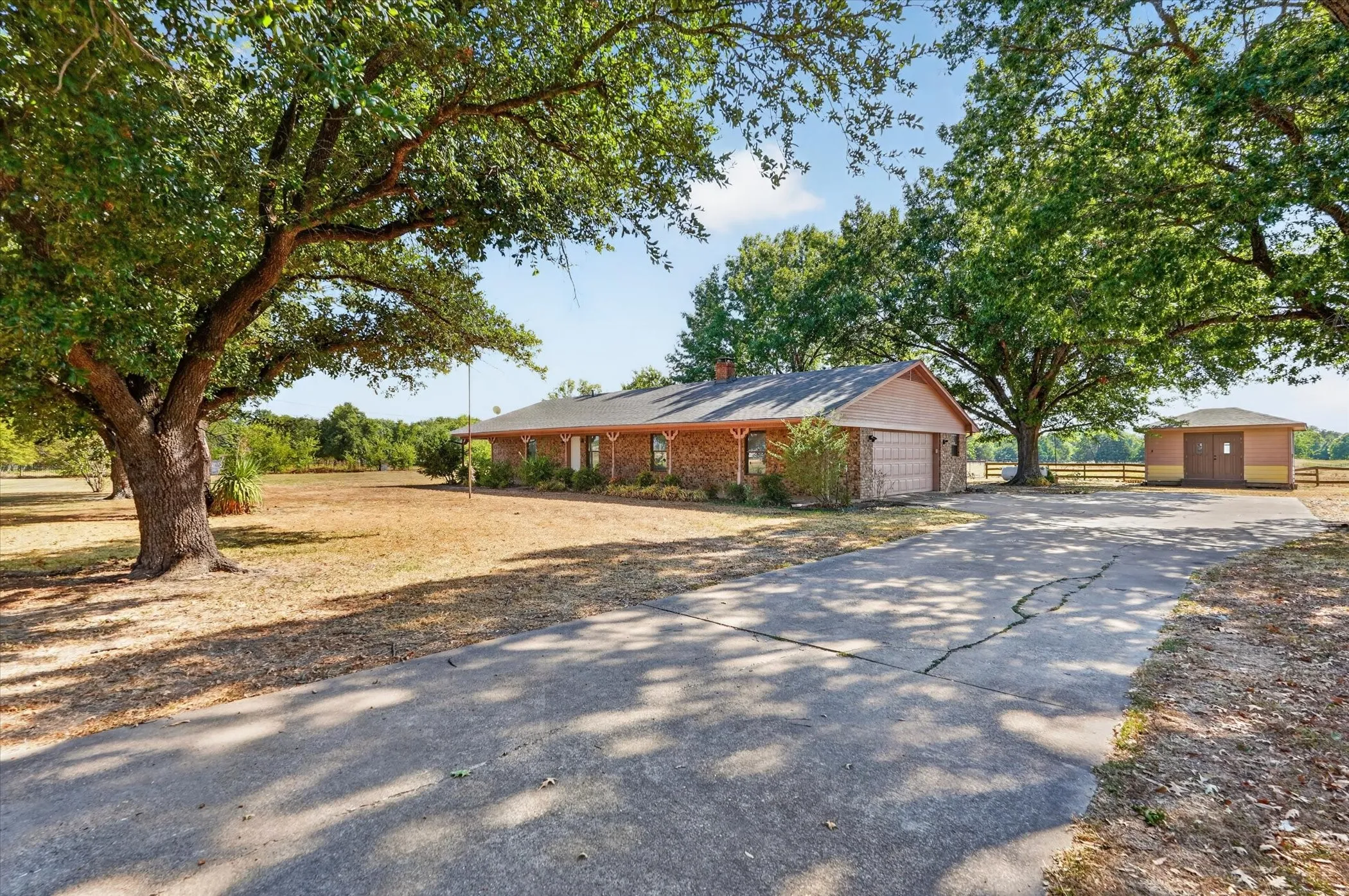 Brick exterior residence with an attached garage, a separate detached outbuilding, and a concrete driveway