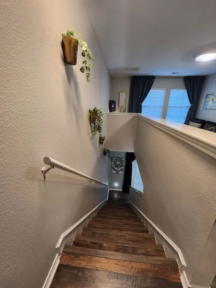 Staircase featuring wood-finish treads, white handrail, and white trim
