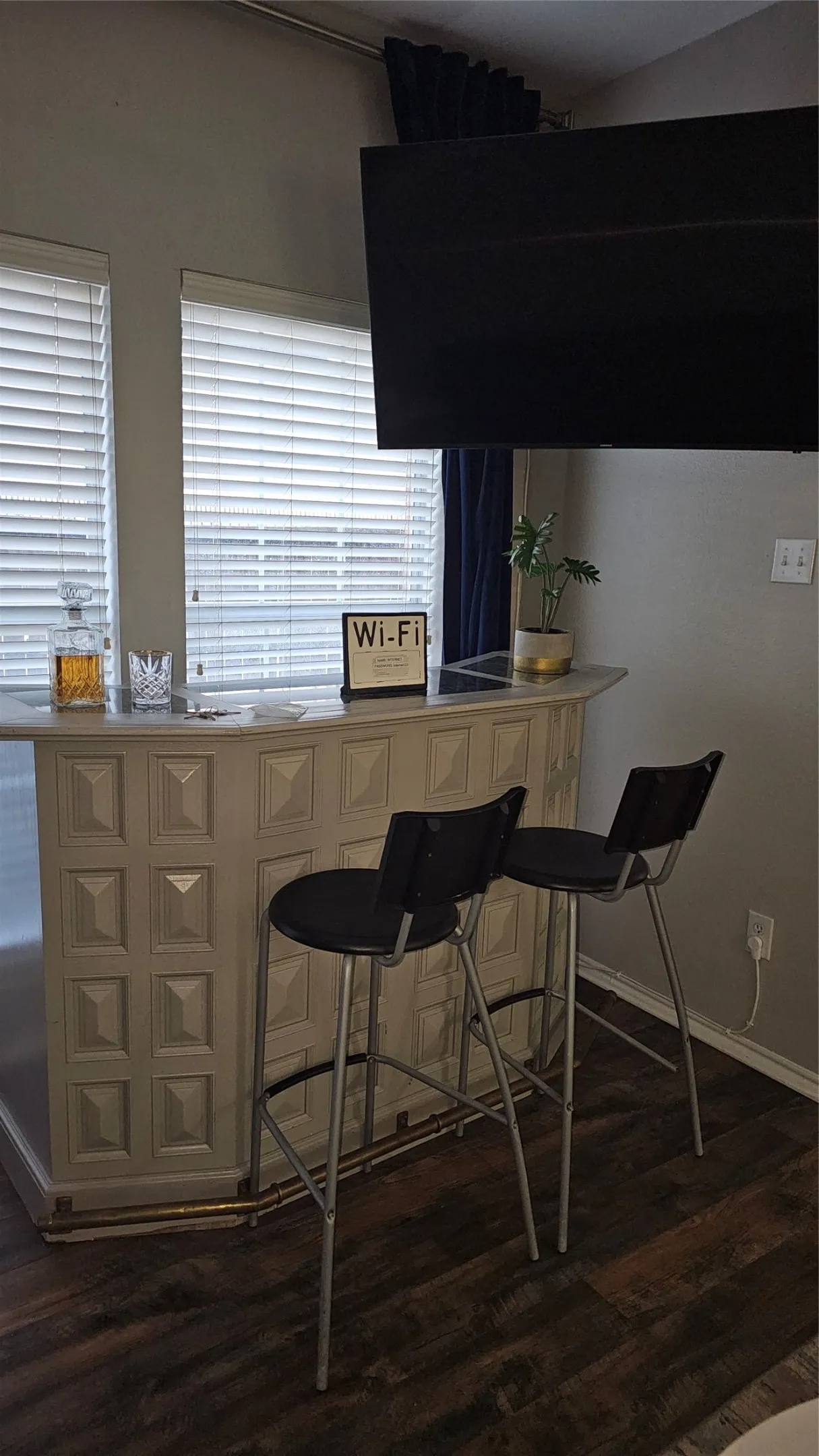 Built-in bar with a light-toned finish, featuring a countertop and dark wood-finish flooring