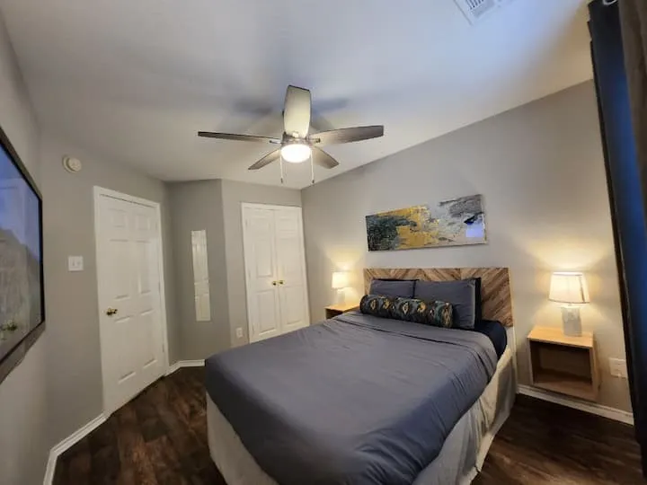 Wood-finish flooring, ceiling fan, white paneled doors, and light gray wall paint