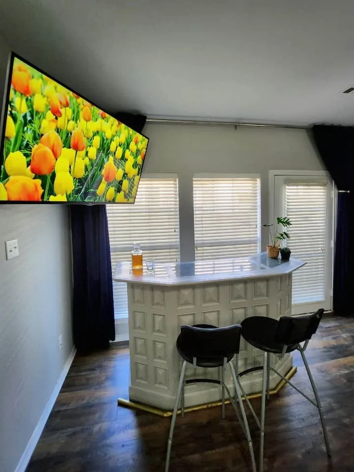 Built-in bar with a light-toned countertop, textured paneling, and a brass-finish foot rail