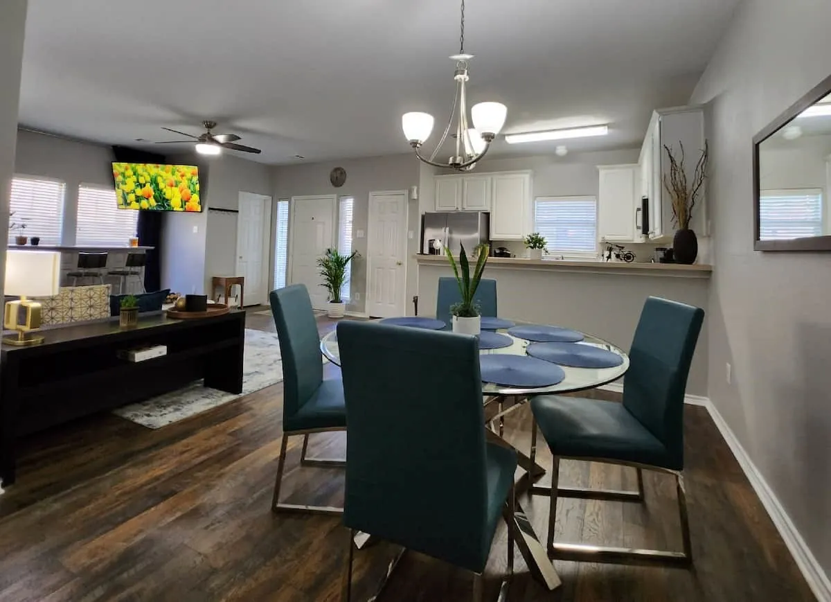 Open-concept living area featuring wood-finish flooring, a contemporary ceiling fan, and a kitchen with white cabinetry and stainless steel appliances