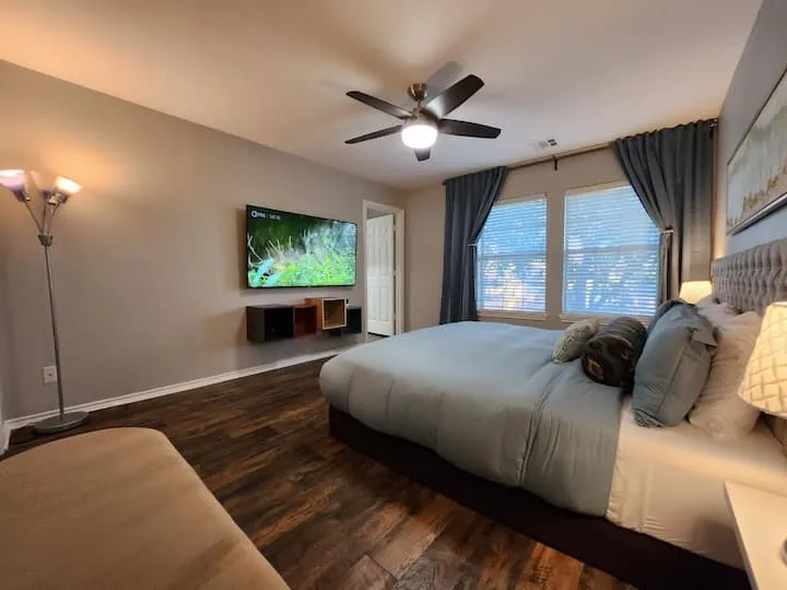 Wood-finish flooring, ceiling fan with integrated lighting, wall-mounted shelving, and multiple windows