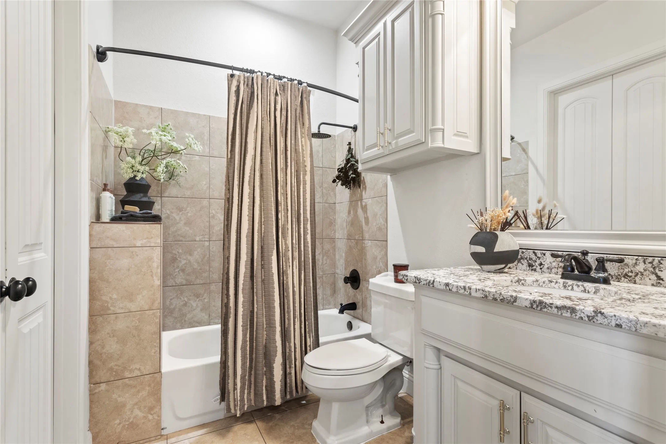 Bathroom featuring a tiled tub surround, shower with rainfall showerhead, and a vanity with a granite countertop and built-in cabinetry