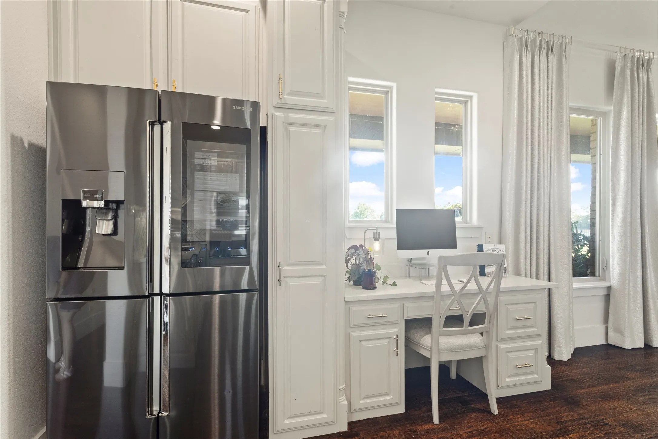 Built-in desk with paneled cabinetry, stainless steel French door refrigerator, and multiple windows with drapery rods