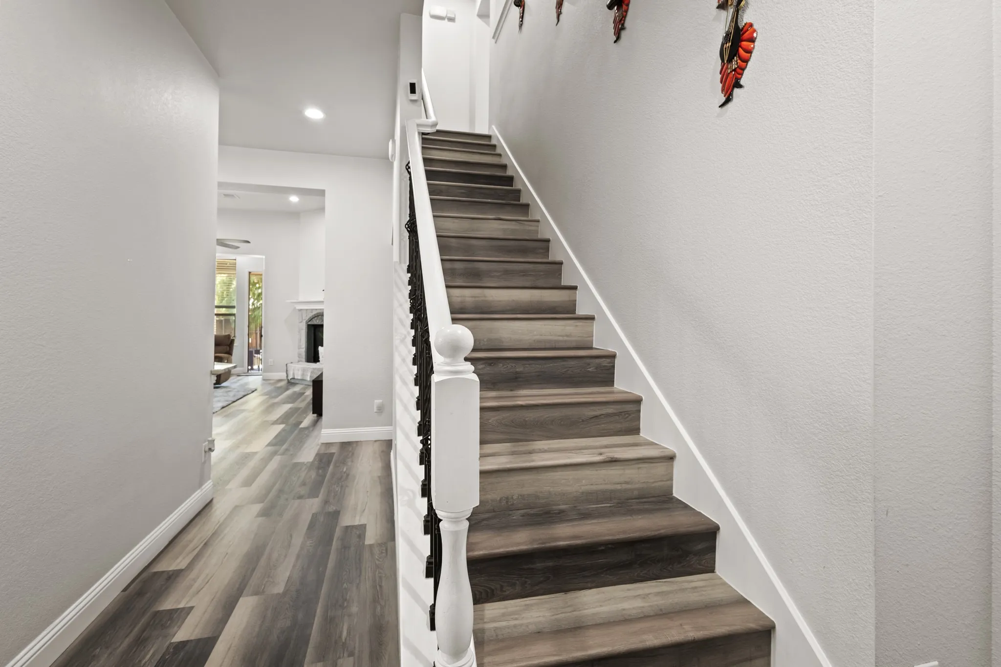 Staircase featuring wood-finish treads, white balusters, and a black wrought iron railing