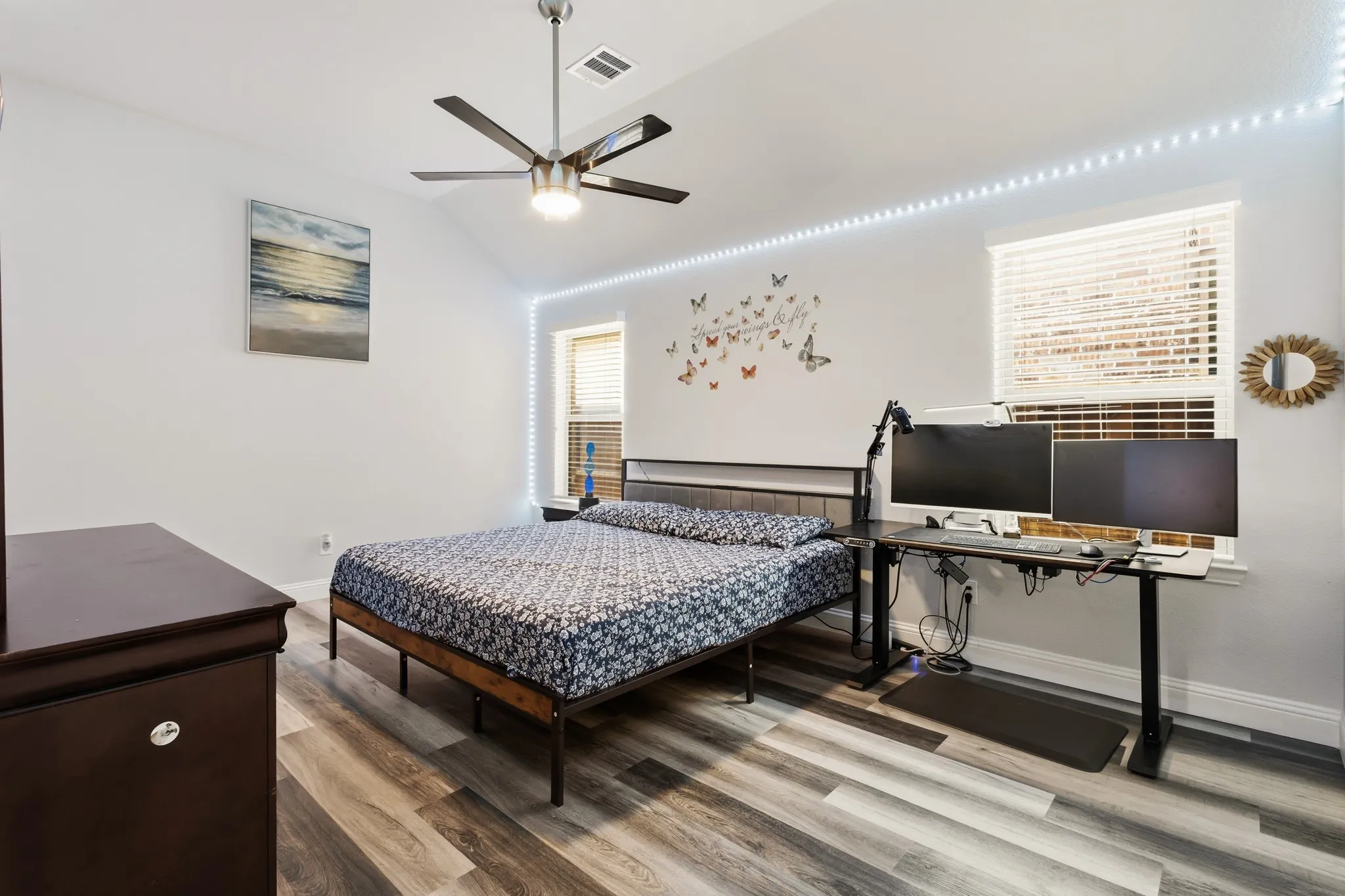 Vaulted ceiling with a ceiling fan, wood-finish flooring, and multiple windows with blinds