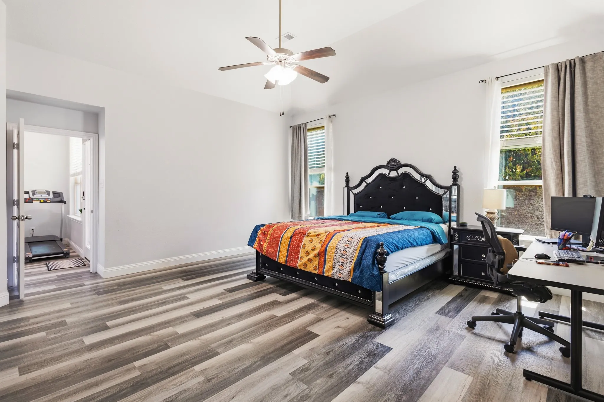Vaulted ceiling with a ceiling fan, wood-finish flooring, and dual windows