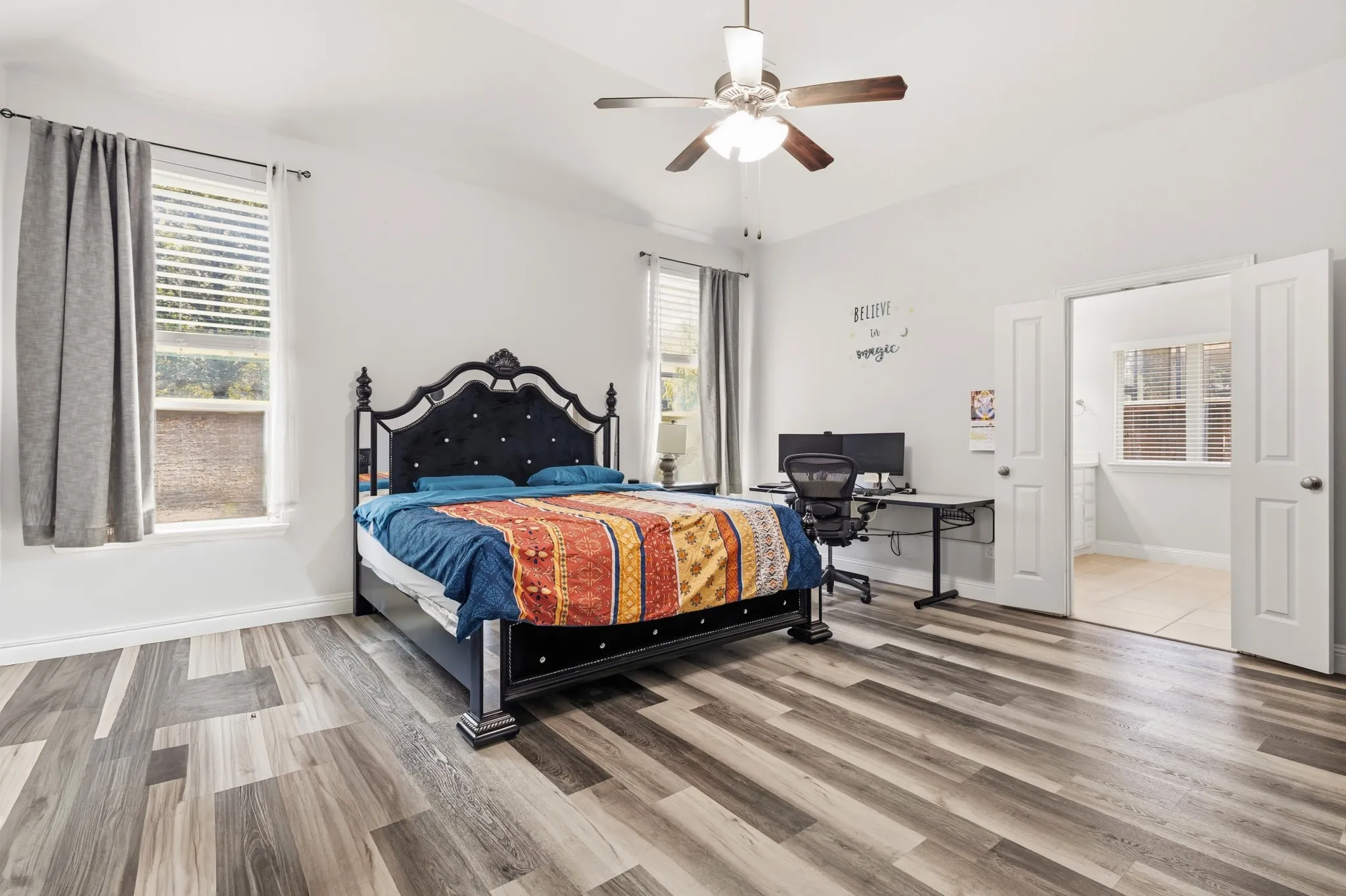 Wood-finish flooring, vaulted ceiling, dual windows with blinds, ceiling fan, and double doors