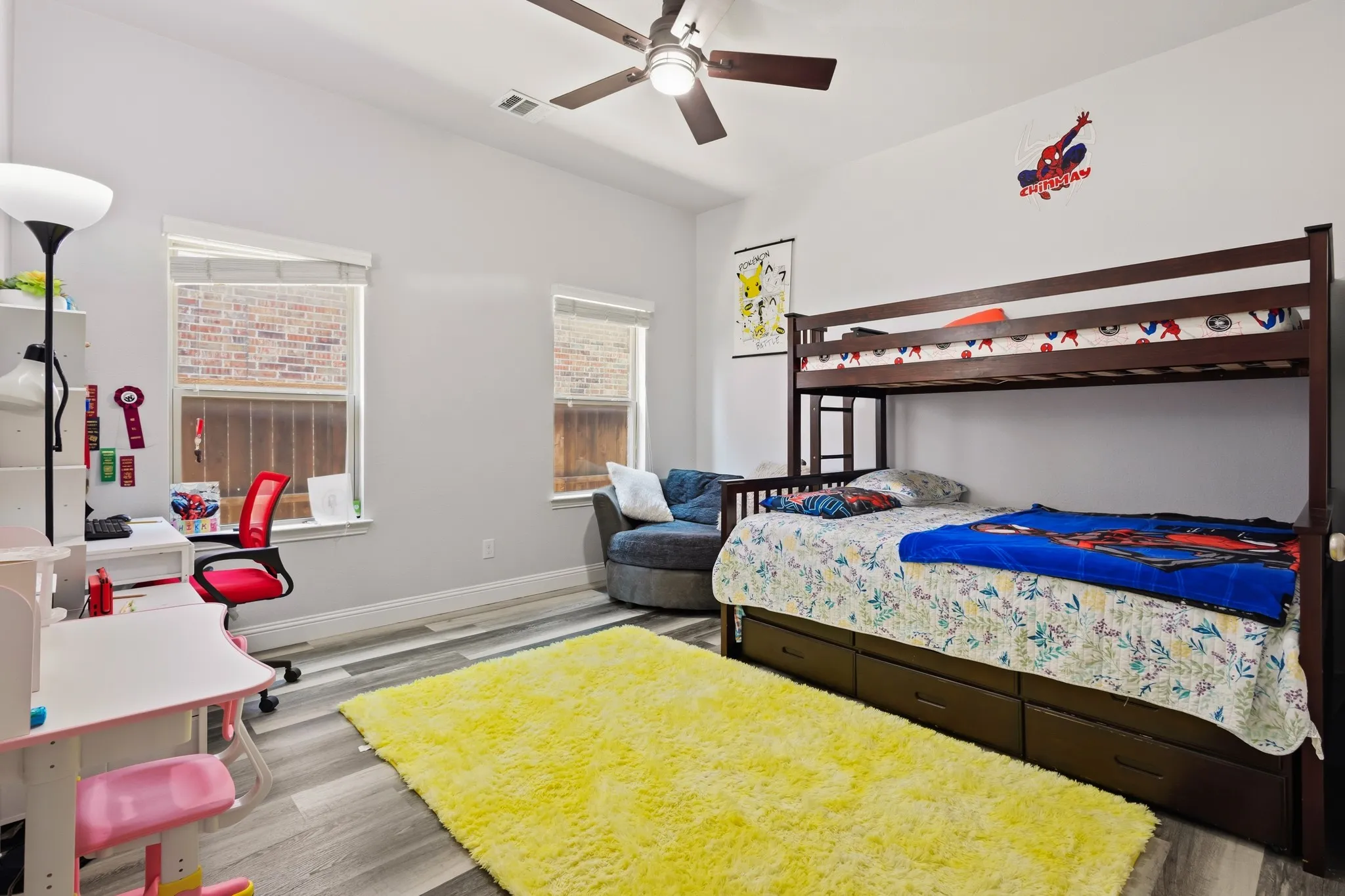 Vaulted ceiling with a ceiling fan, two windows with blinds, and wood-finish flooring