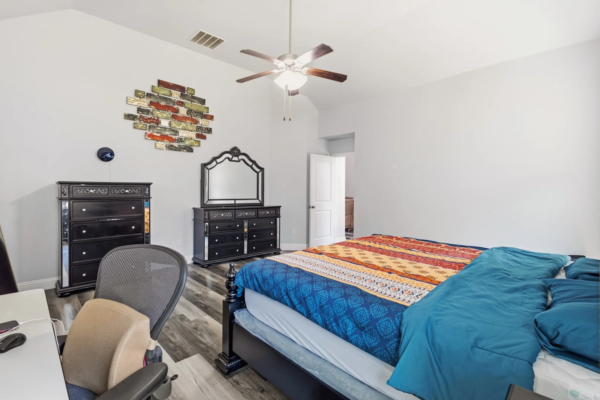 Vaulted ceiling with a ceiling fan, wood-finish flooring, and white walls