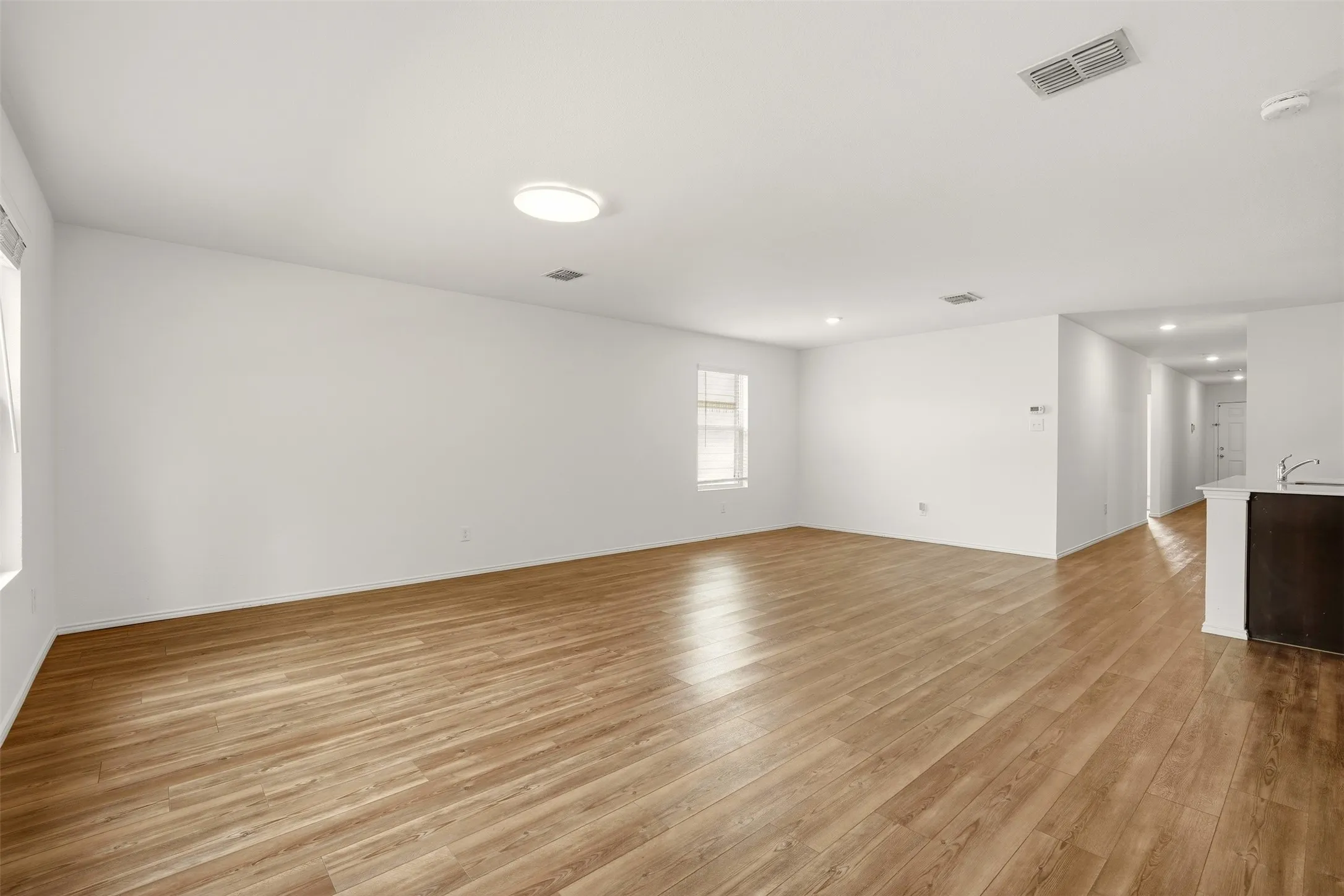 Spacious room featuring wood-finish flooring, white walls, multiple windows, and recessed lighting