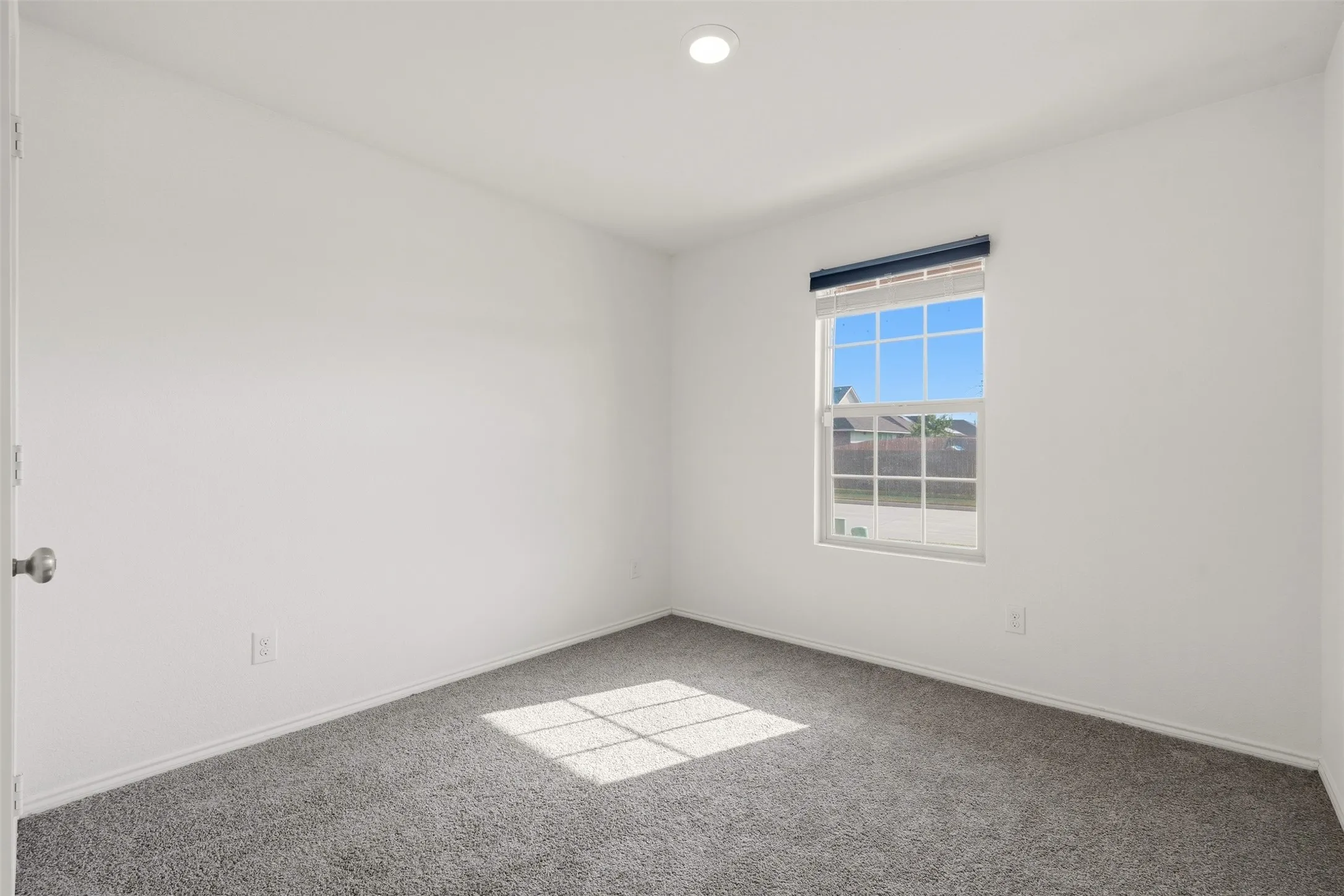 Neutral wall paint, recessed ceiling lighting, window with grid panes, and gray carpet
