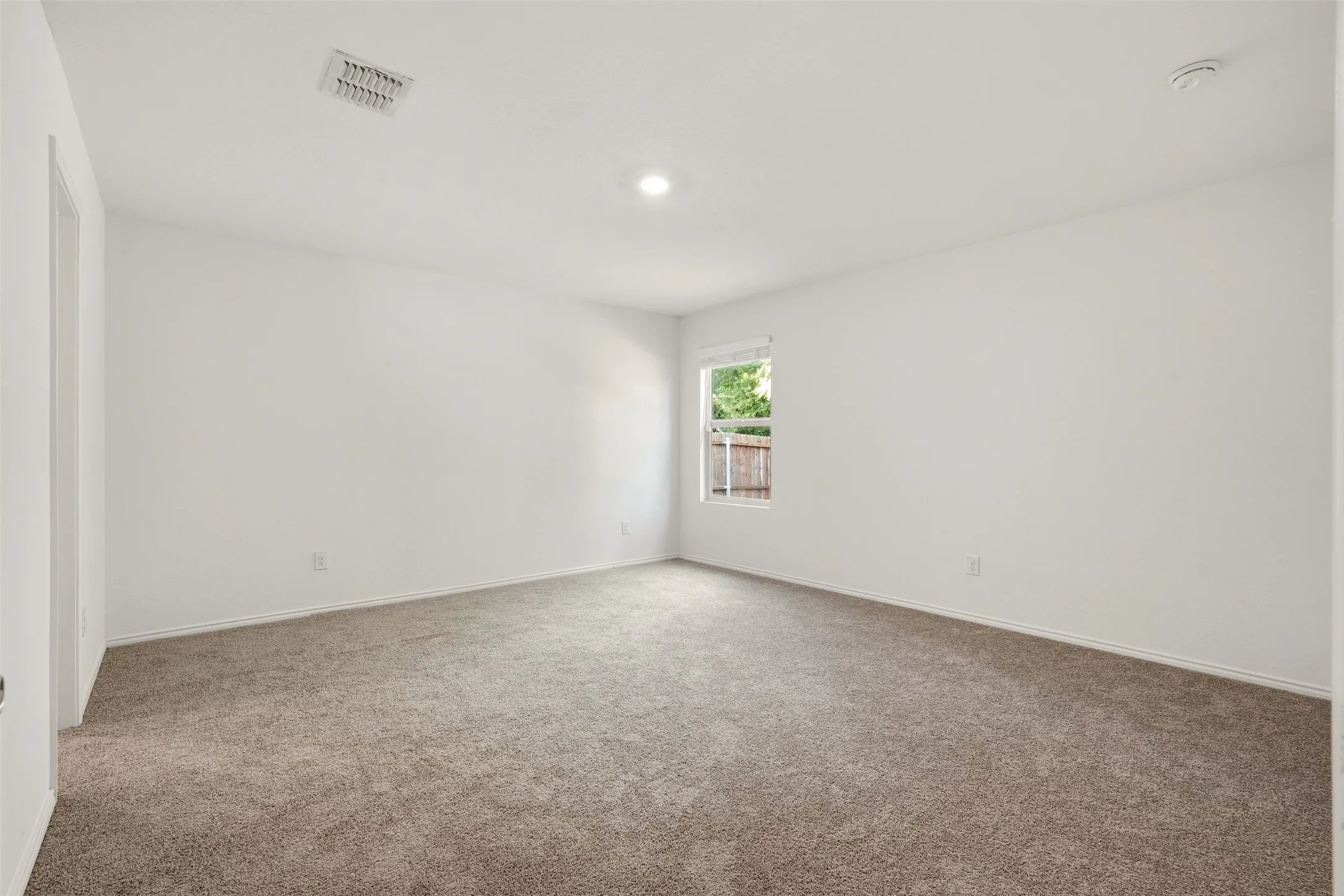 Neutral-toned carpeting with white walls and a single window