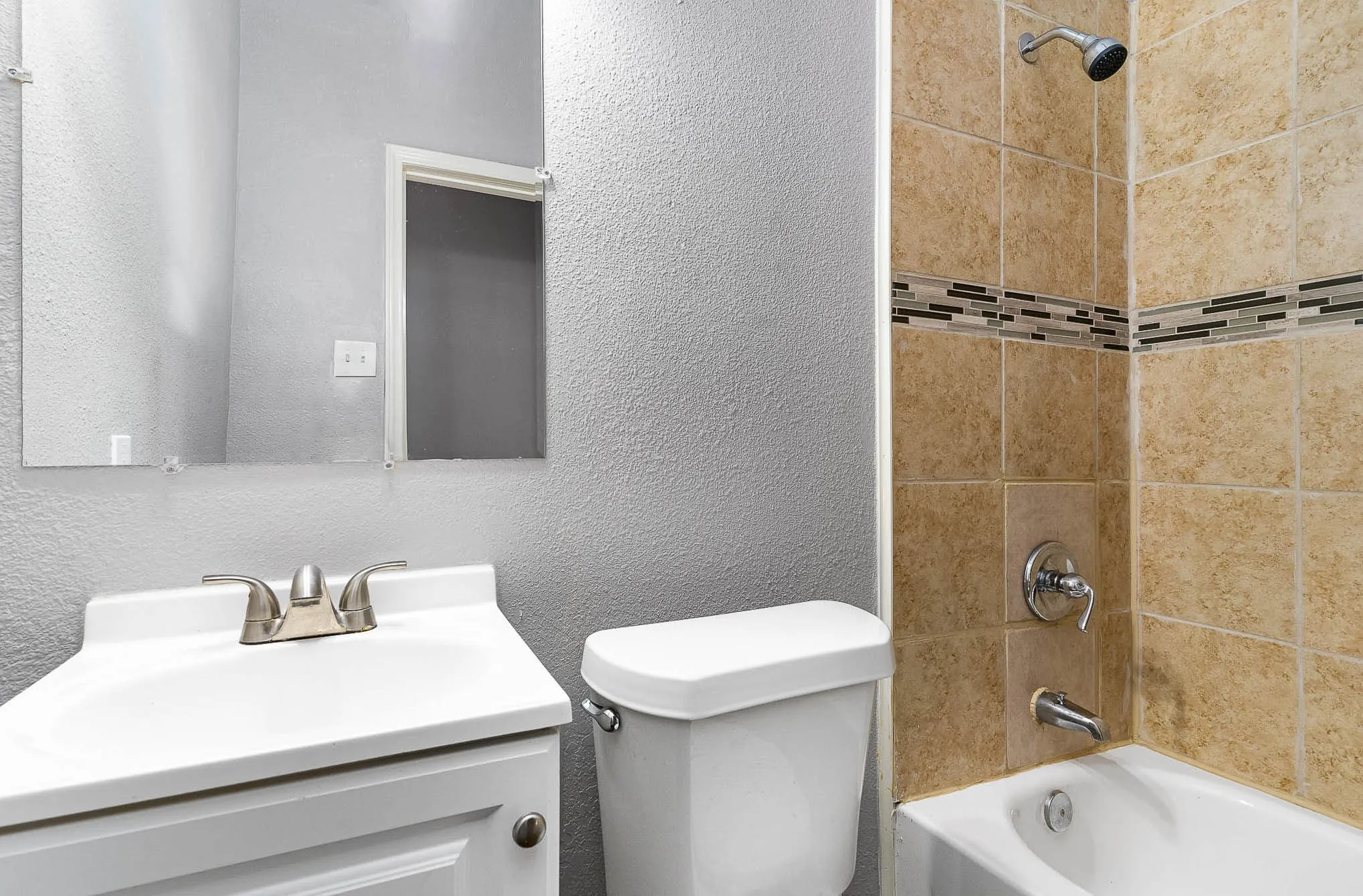 Full bathroom featuring a textured wall, toilet, tub / shower combination, and vanity
