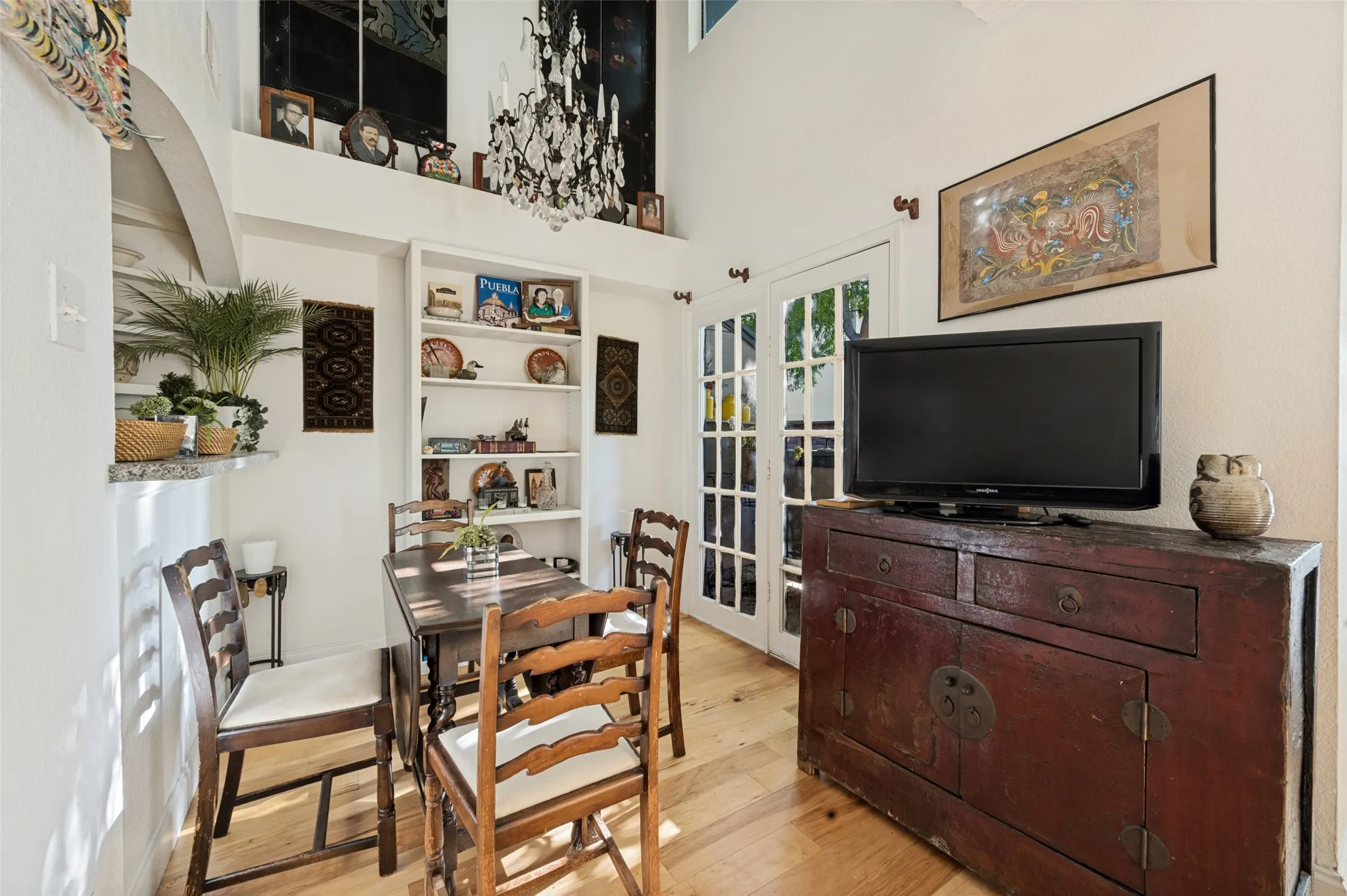 Hardwood flooring, built-in shelving, high ceilings, French doors, and an arched architectural detail