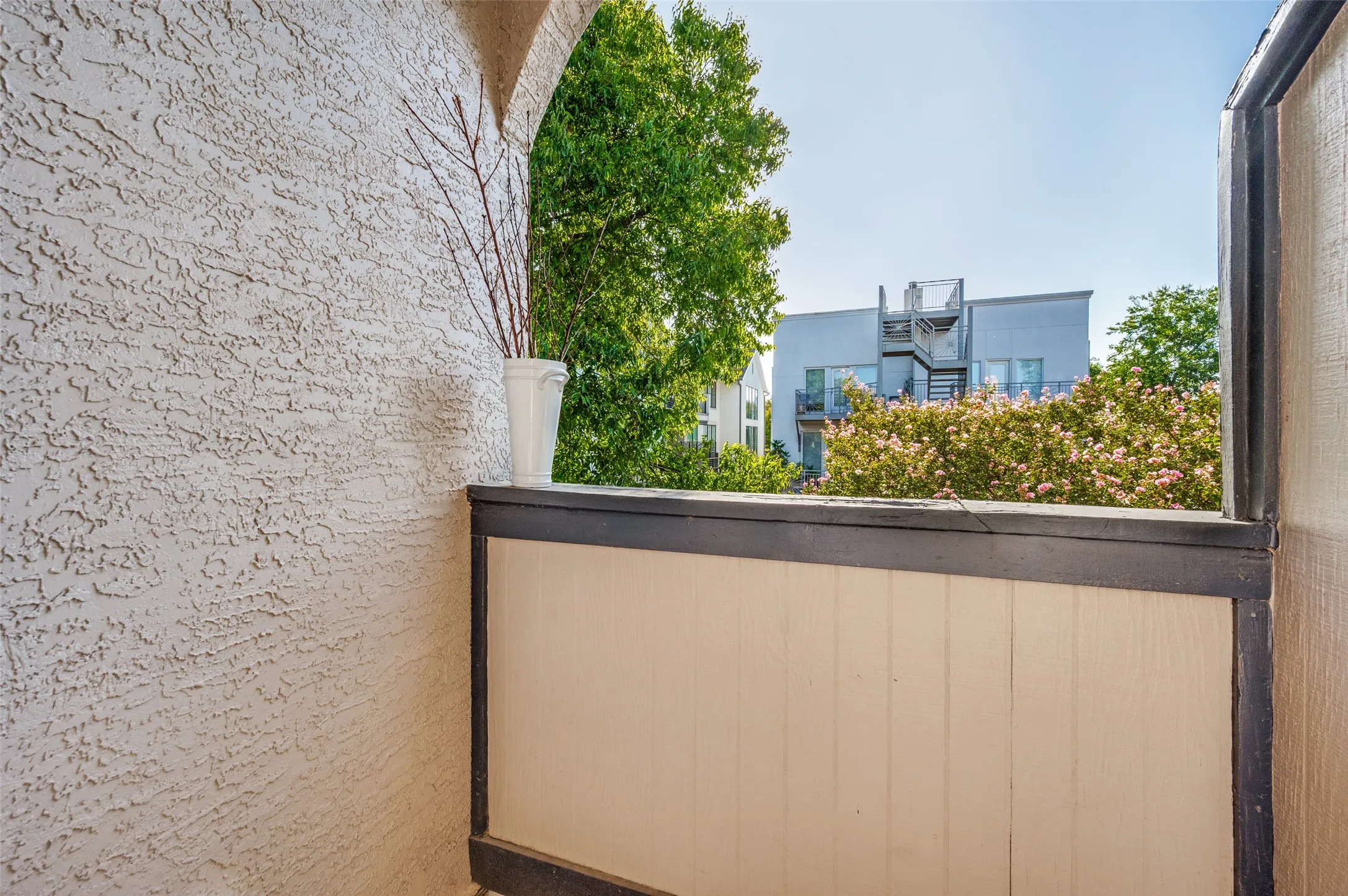 Private balcony with textured stucco wall and wood-paneled railing