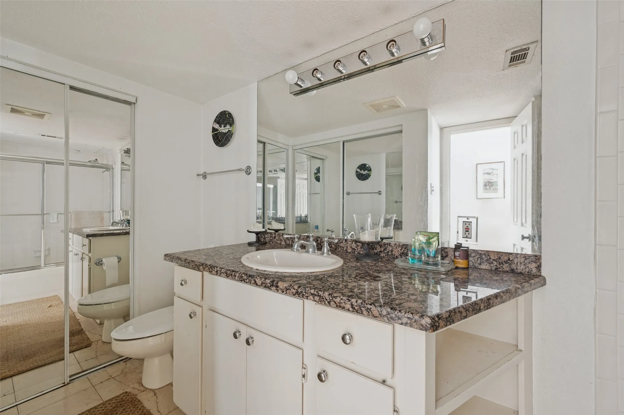 Vanity with a granite-style countertop, integrated sink, and white cabinetry