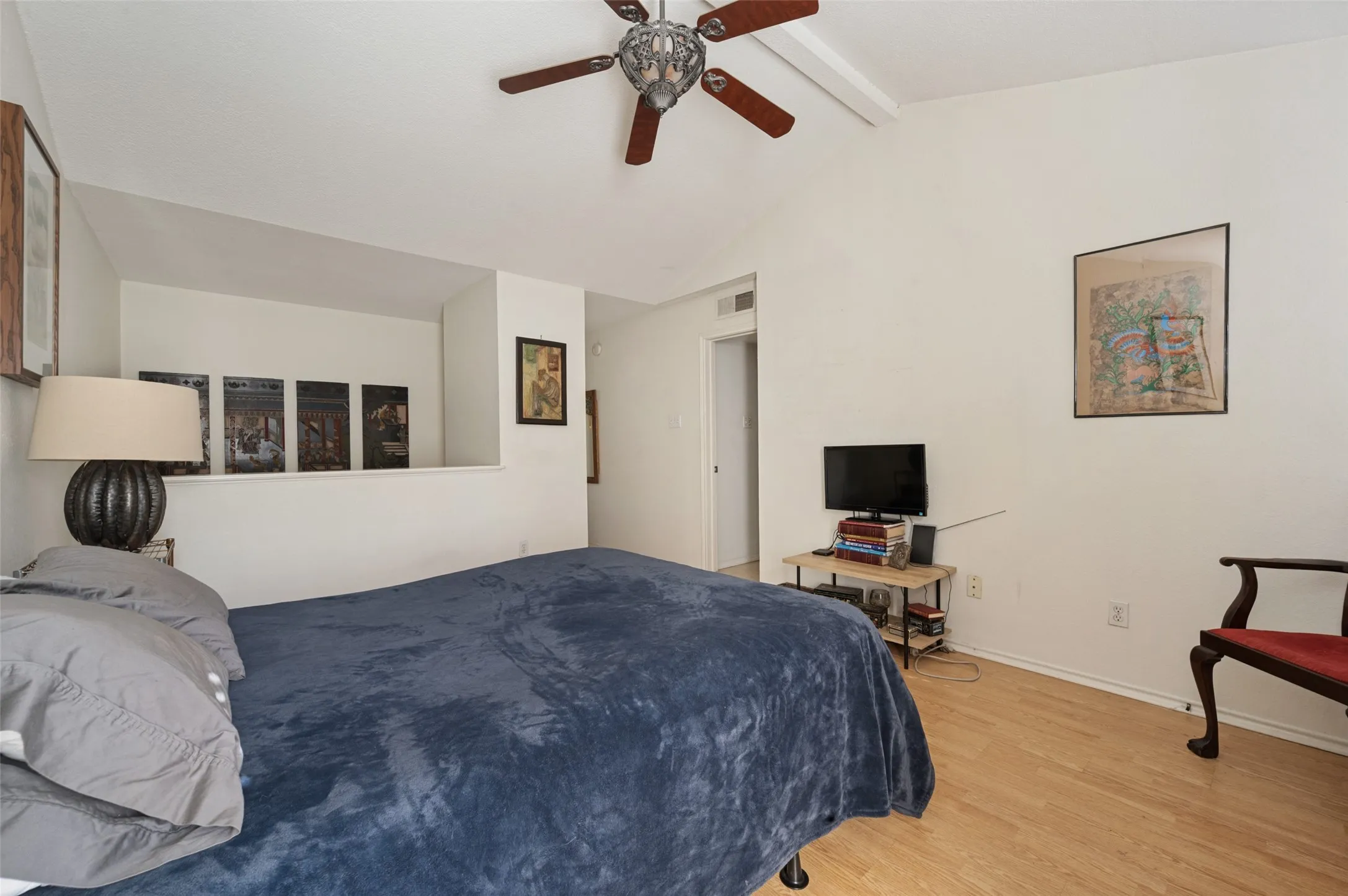 Vaulted ceiling with a ceiling fan, light wood-finish flooring, and a partial wall separation