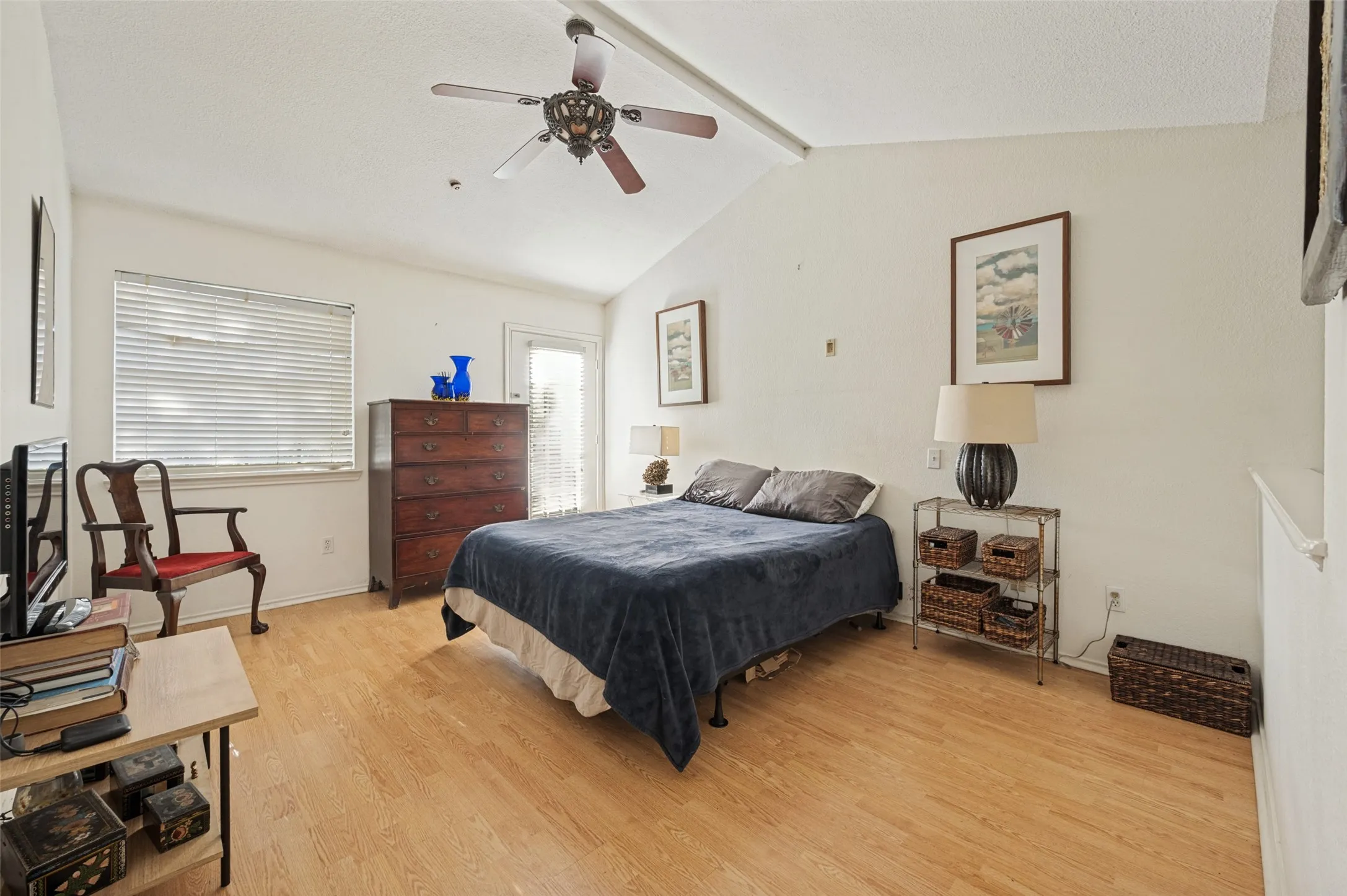 Vaulted ceiling with a ceiling fan, wood-finish flooring, and a glass-paned door