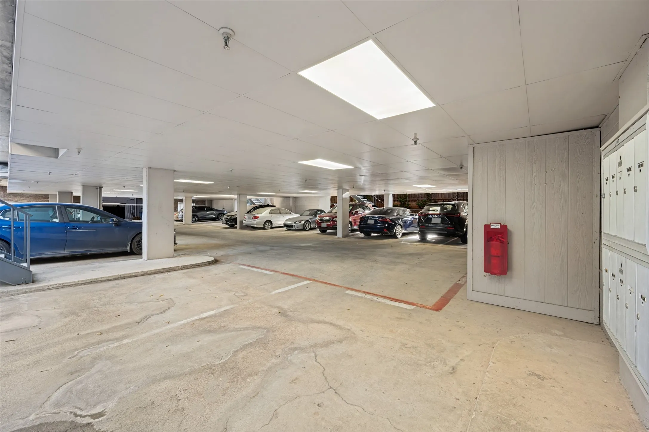 Covered parking area featuring concrete flooring, recessed lighting, and a wall of mailboxes