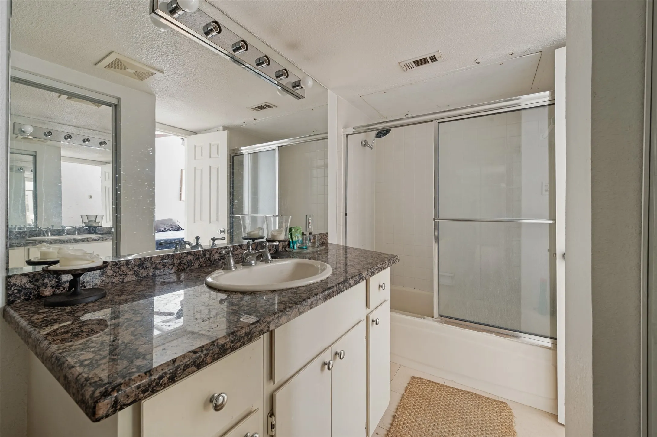Vanity with a polished stone countertop and integrated sink, mirrored wall, and built-in cabinetry