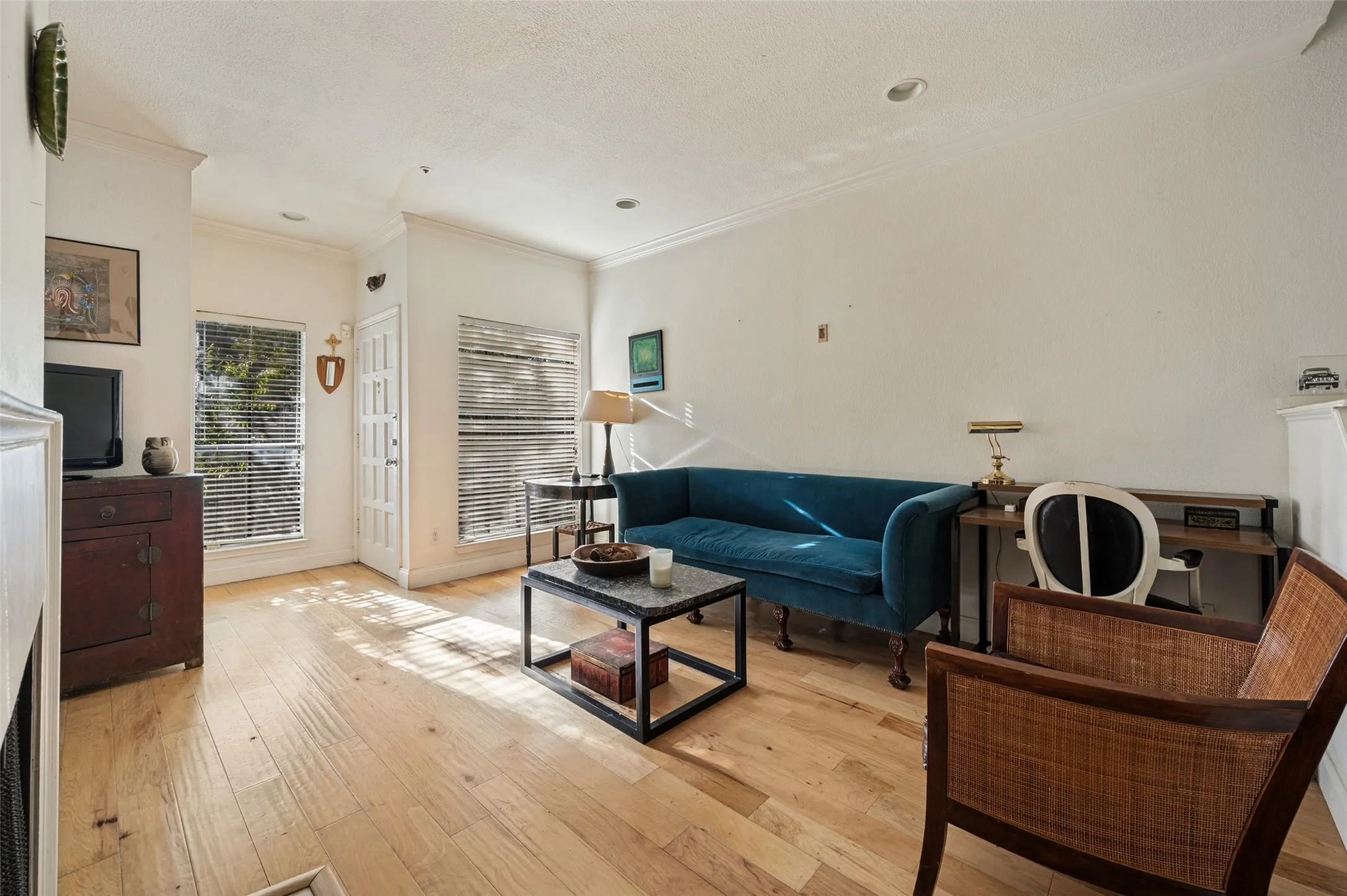 Hardwood-finish flooring, crown molding, a built-in fireplace, recessed lighting, and a white paneled entry door