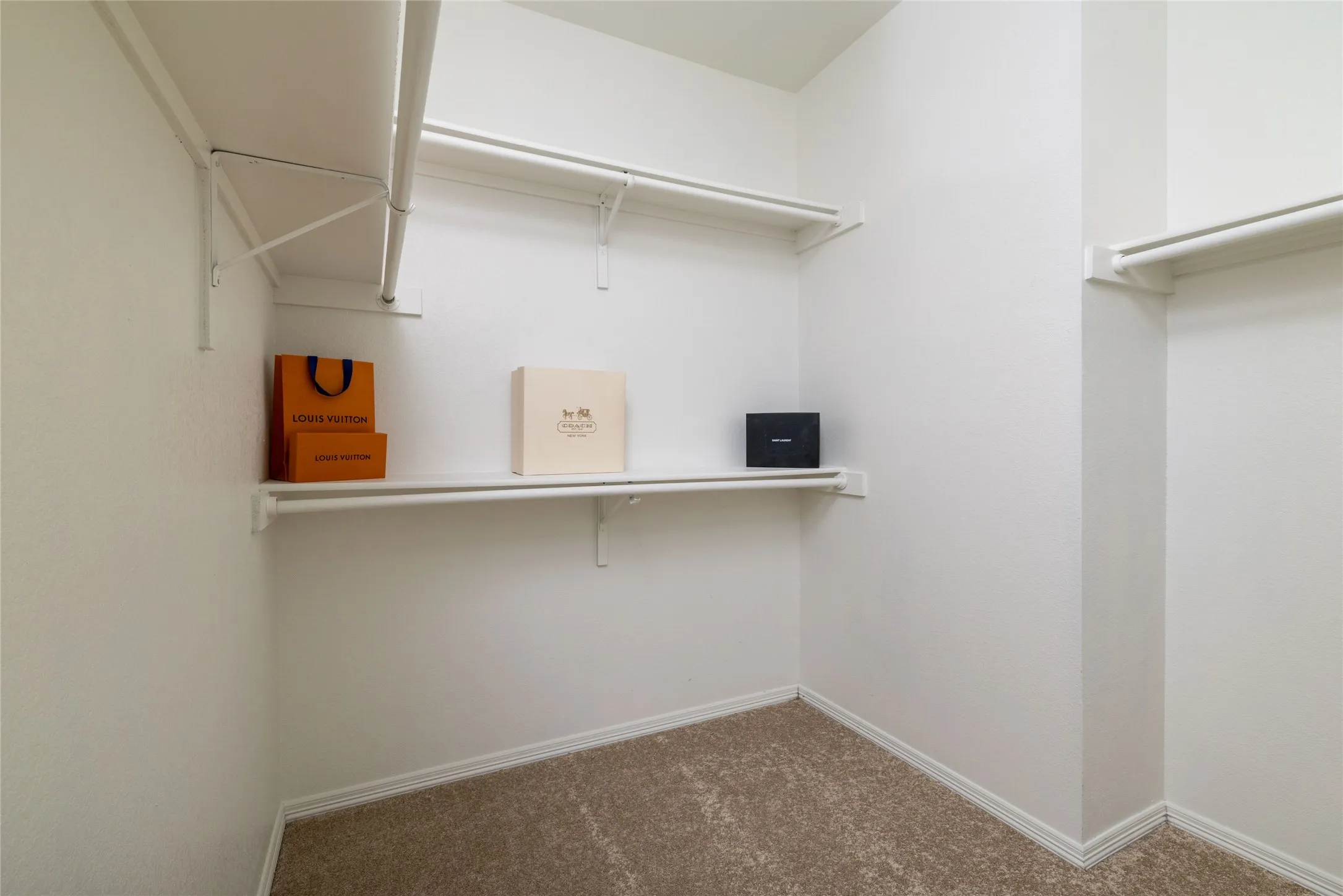 Walk-in closet featuring white wire shelving, hanging rods, and neutral-toned carpeting