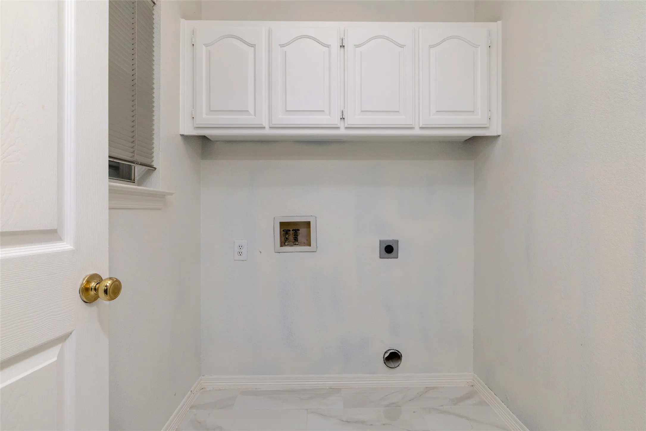 White shaker-style cabinetry with arched paneling, light-toned wall paint, and marble-look floor tiling
