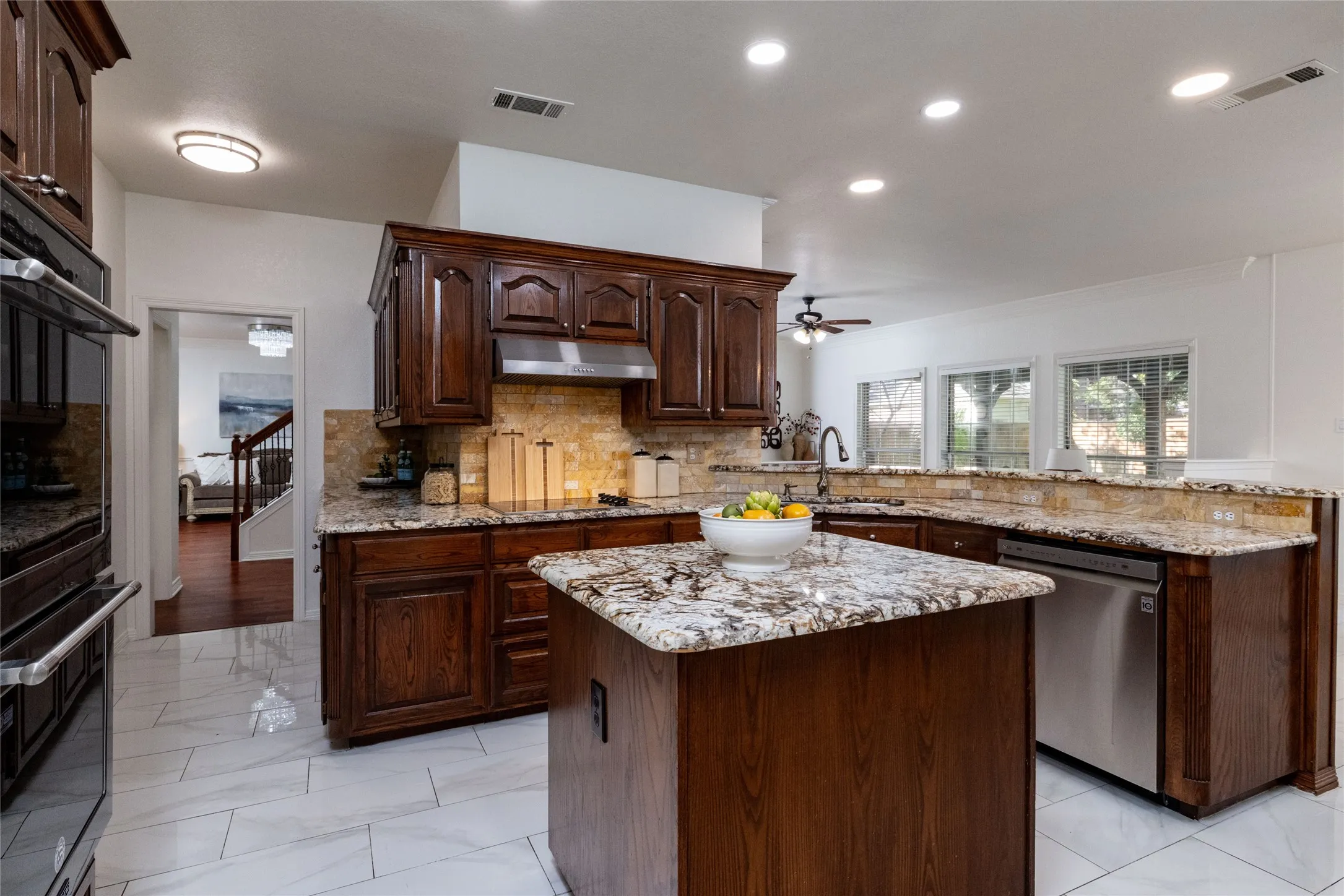 Kitchen featuring wood cabinetry, stone countertops, a tile backsplash, stainless steel appliances, and tile flooring
