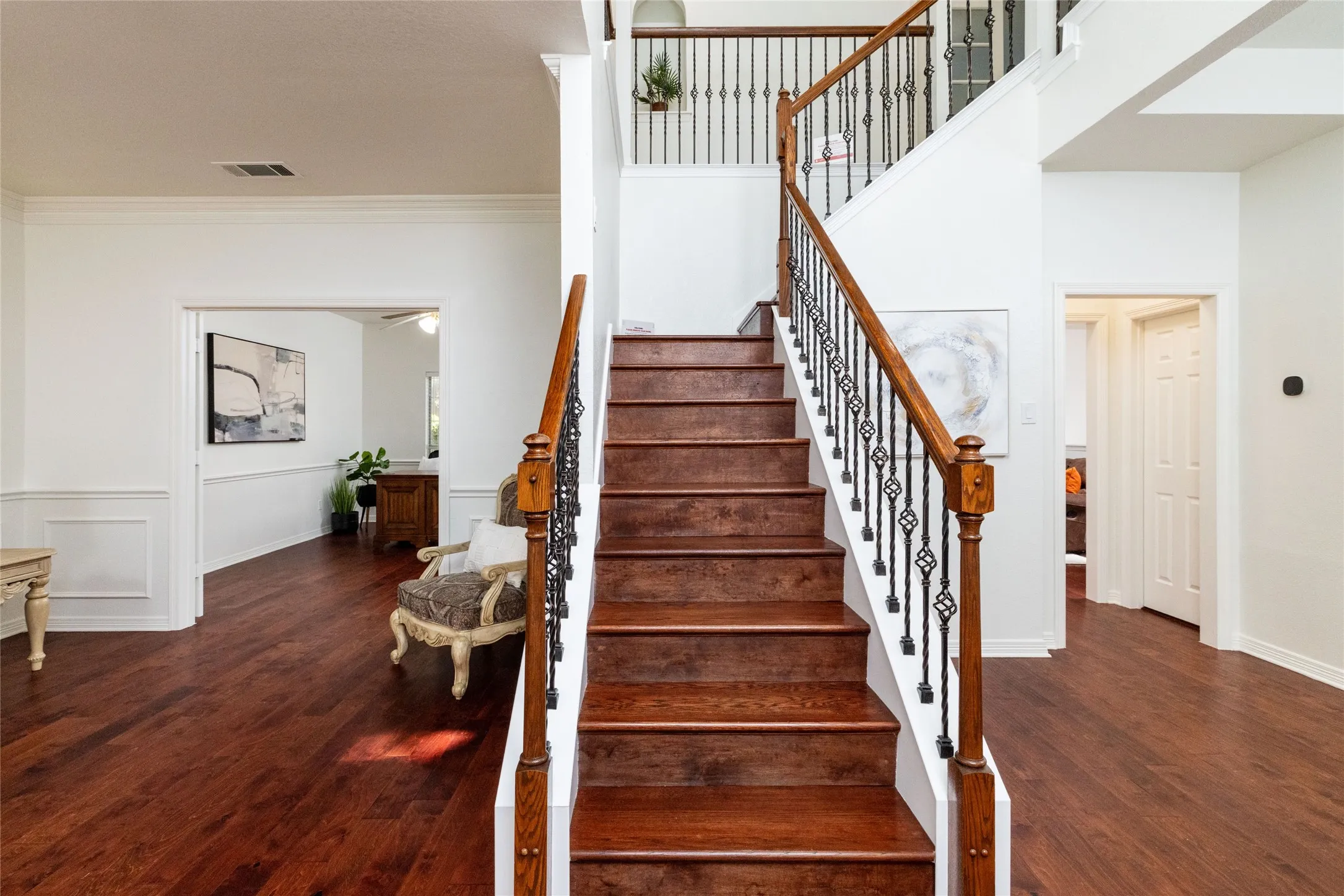 Grand staircase featuring wood treads and wrought iron balusters