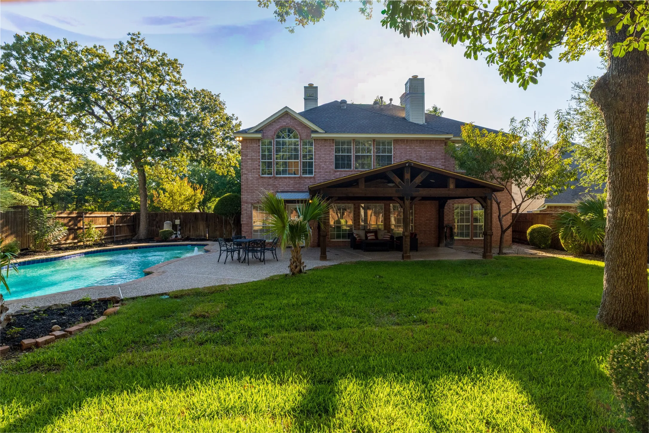 Brick exterior with multiple chimneys, a swimming pool, and a covered patio structure