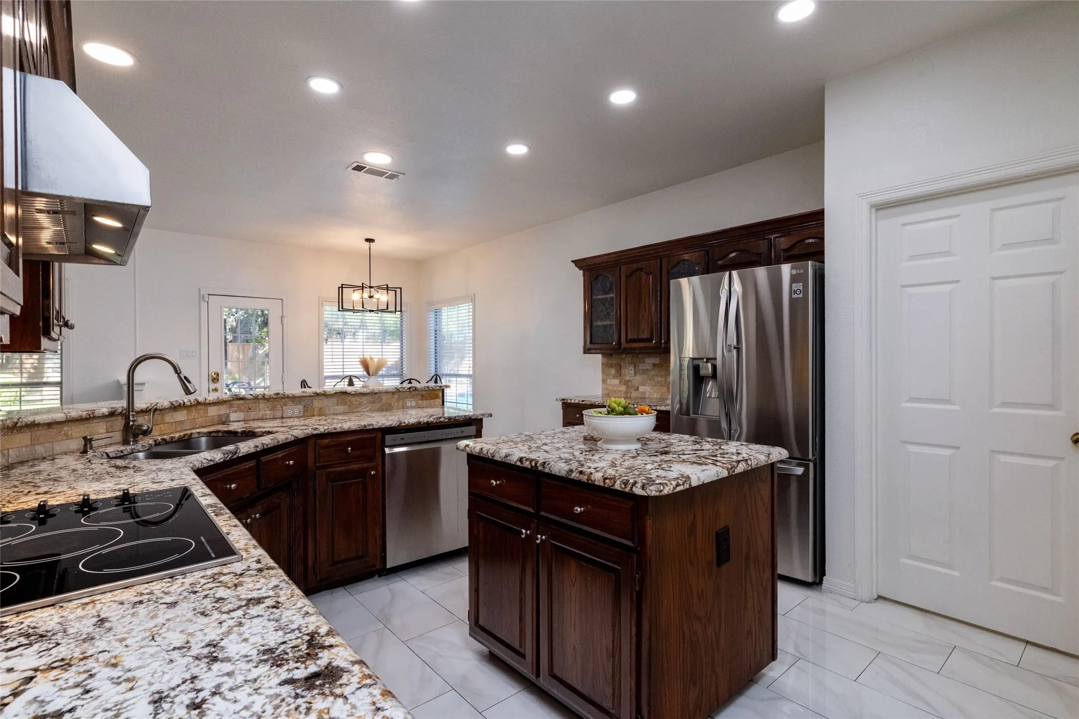 Kitchen featuring granite countertops, wood-finish cabinetry, stainless steel appliances, a center island, and recessed lighting