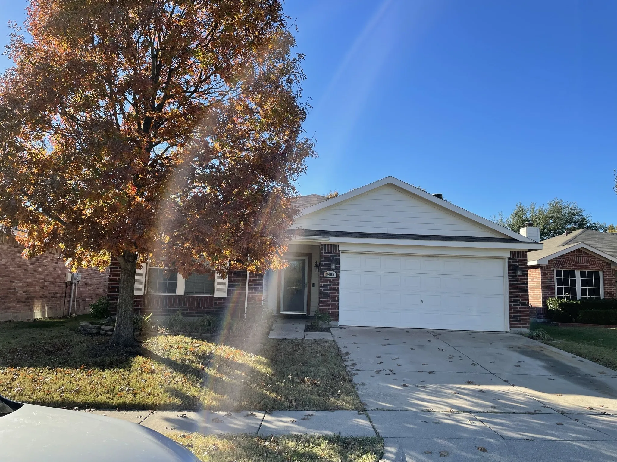 Brick exterior with white siding accents, an attached two-car garage, and a concrete driveway