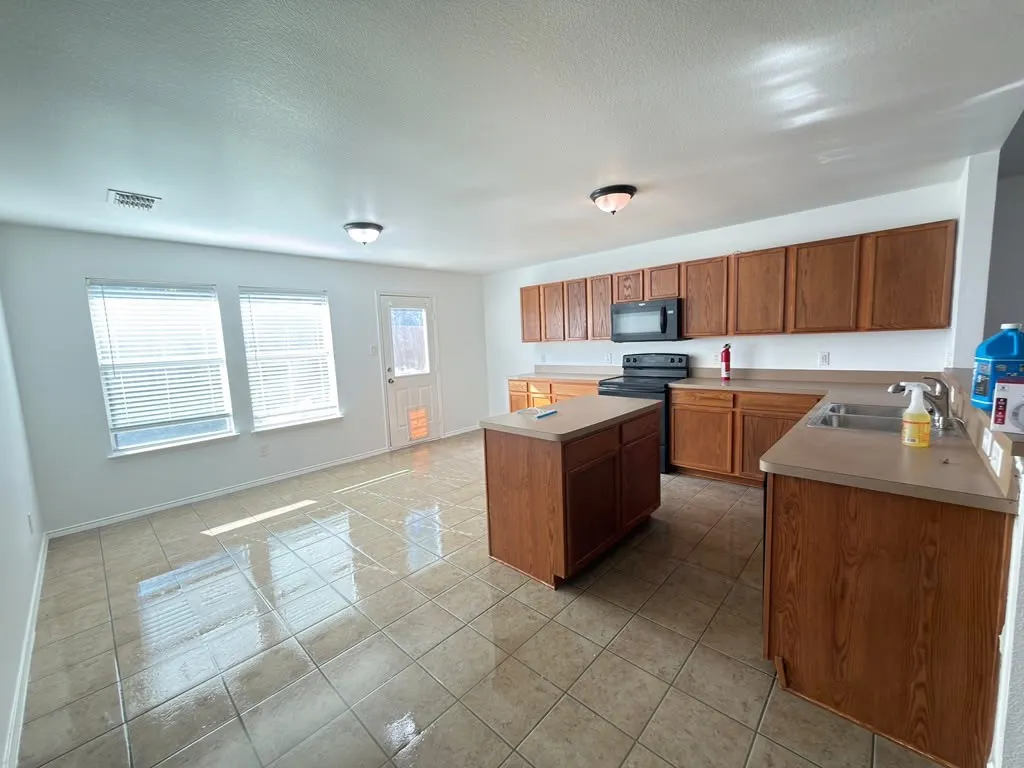 Kitchen with wood-finish cabinetry, a central island, and tile flooring