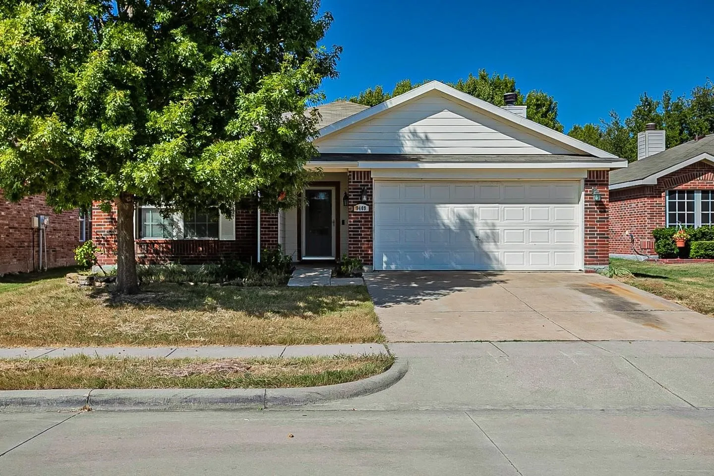 Red brick exterior with white siding accents and a two-car garage