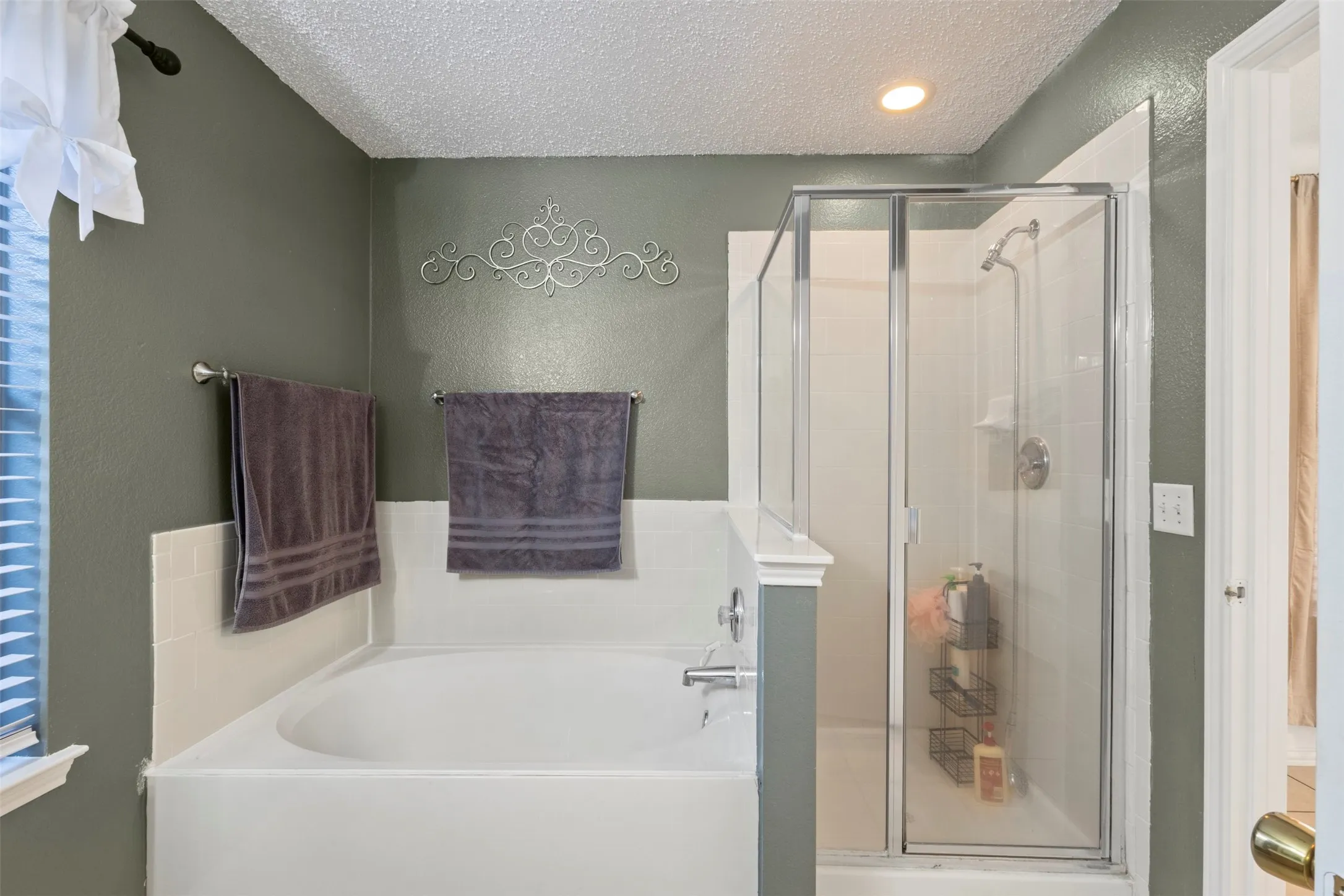 Built-in tub and separate glass-enclosed shower with a recessed ceiling light